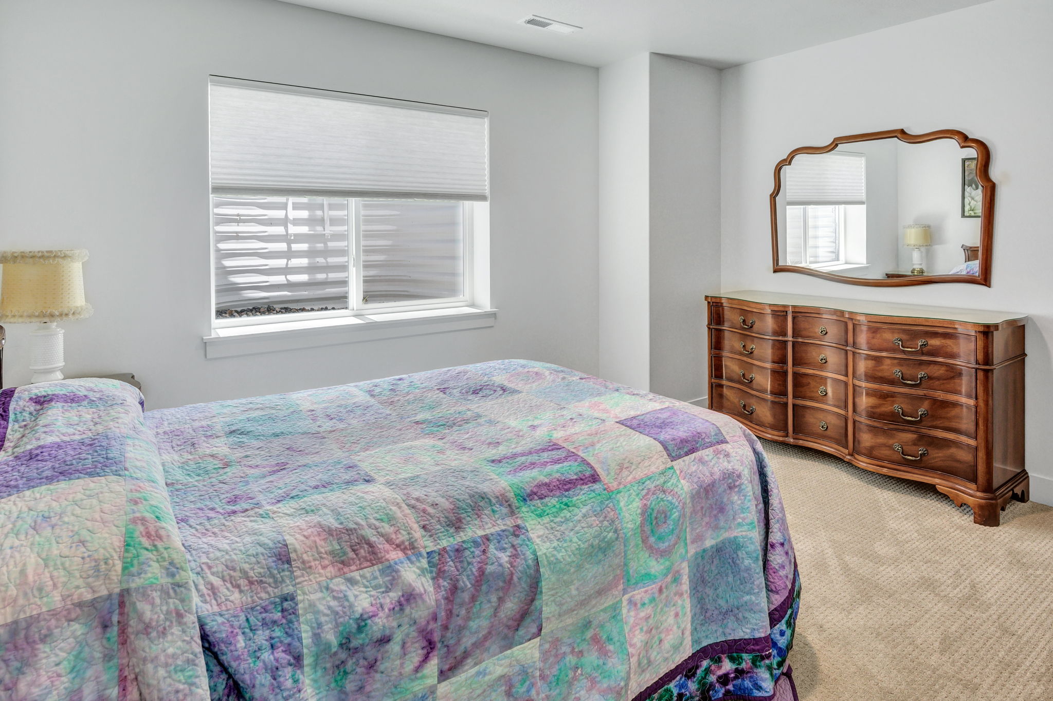 Carpeted interior space featuring a window with cellular shades, a white window frame, and neutral wall tones