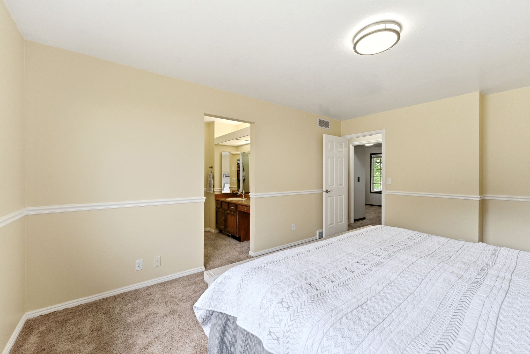 Carpeted room featuring light beige walls with white chair rail molding, a white paneled door, and a flush-mount ceiling light fixture