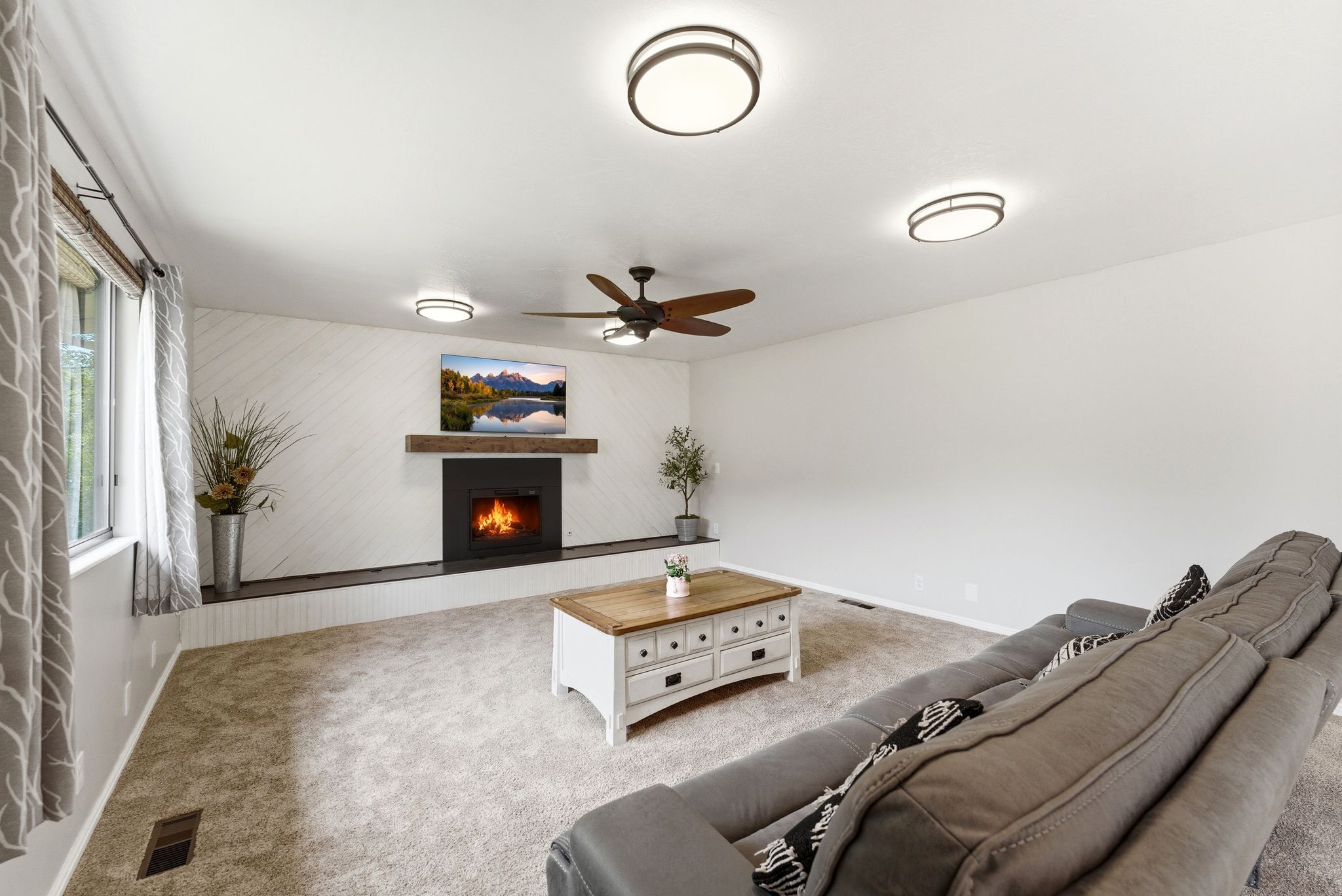 Living area featuring a modern fireplace with a black surround, a wood mantel, and a textured white accent wall