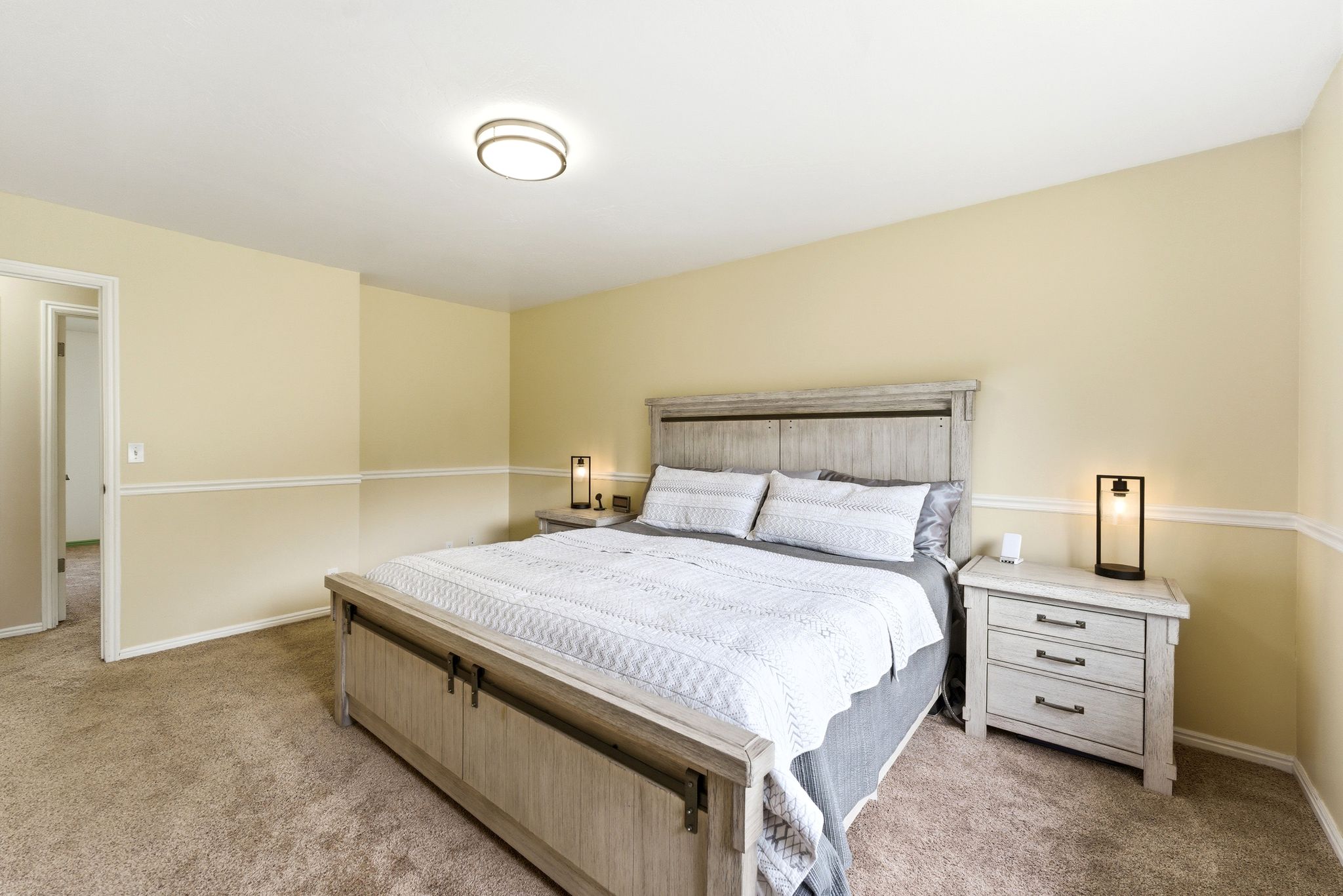 Carpeted room with light yellow walls and white chair rail molding