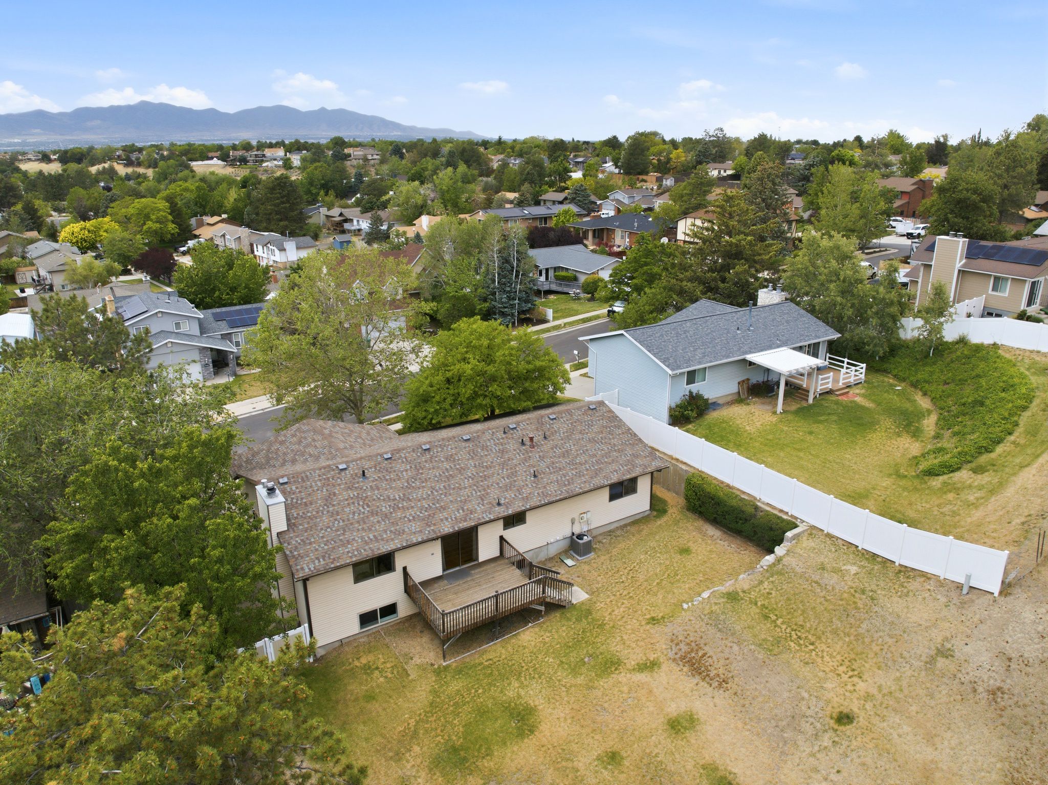 Rear exterior featuring a wood deck, white vinyl privacy fence, and a neutral-toned facade