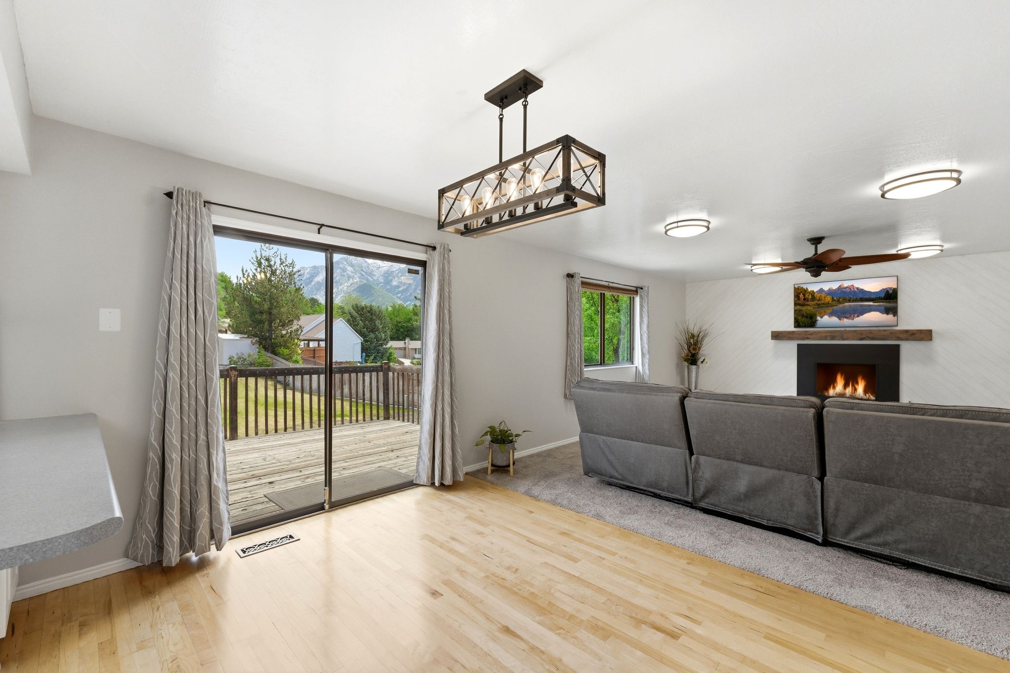 Living area with wood-finish flooring, a wall-mounted fireplace, and a wood mantel