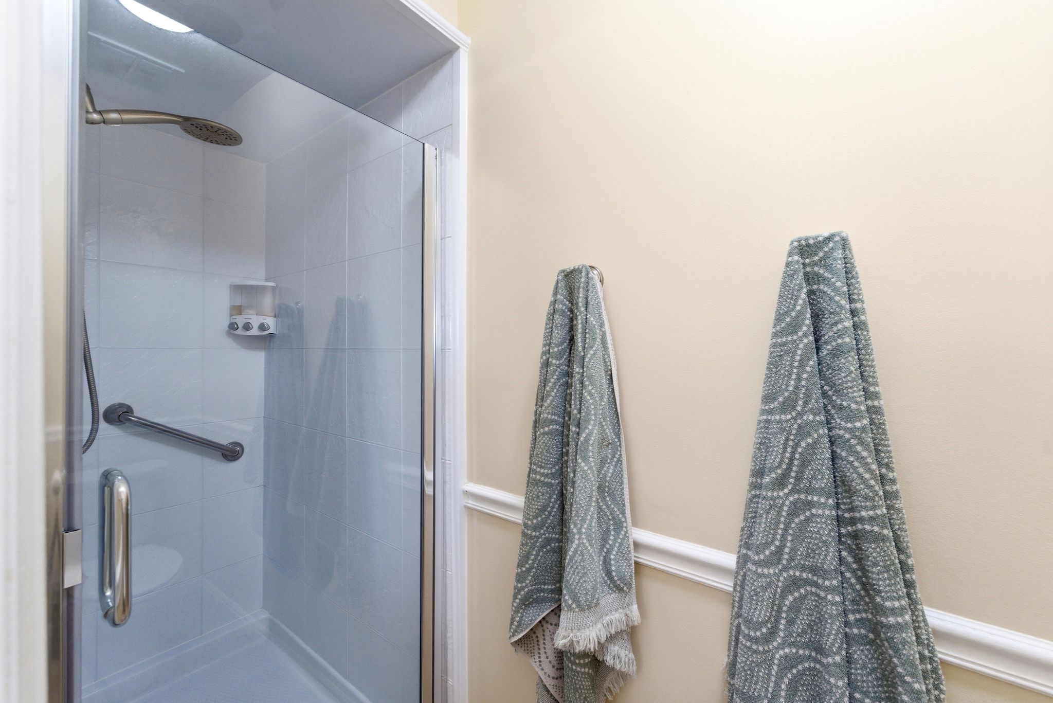 Enclosed shower with a glass door, brushed nickel fixtures, and a wall-mounted grab bar