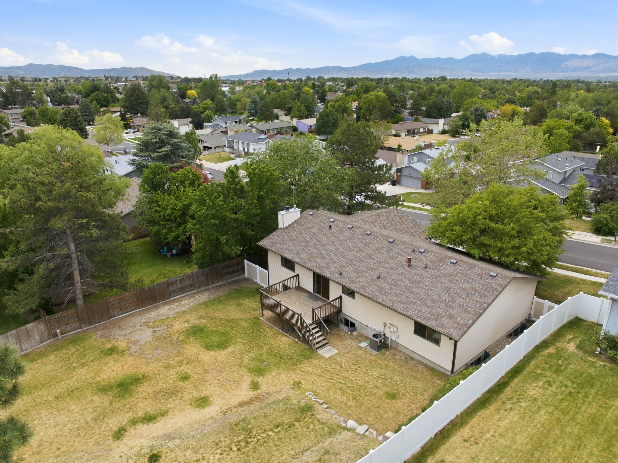 Expansive rear yard featuring a wood privacy fence and a white vinyl fence