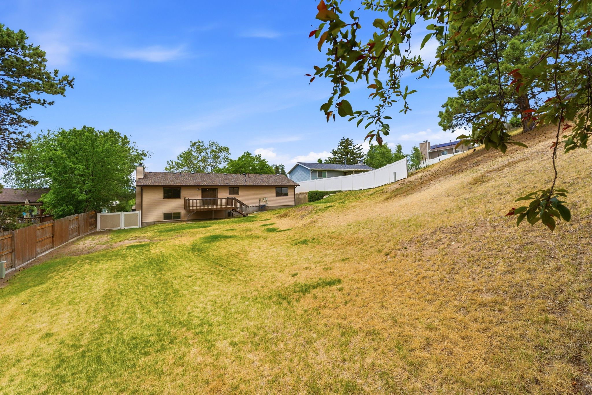 Expansive rear yard featuring varied terrain and partial fencing