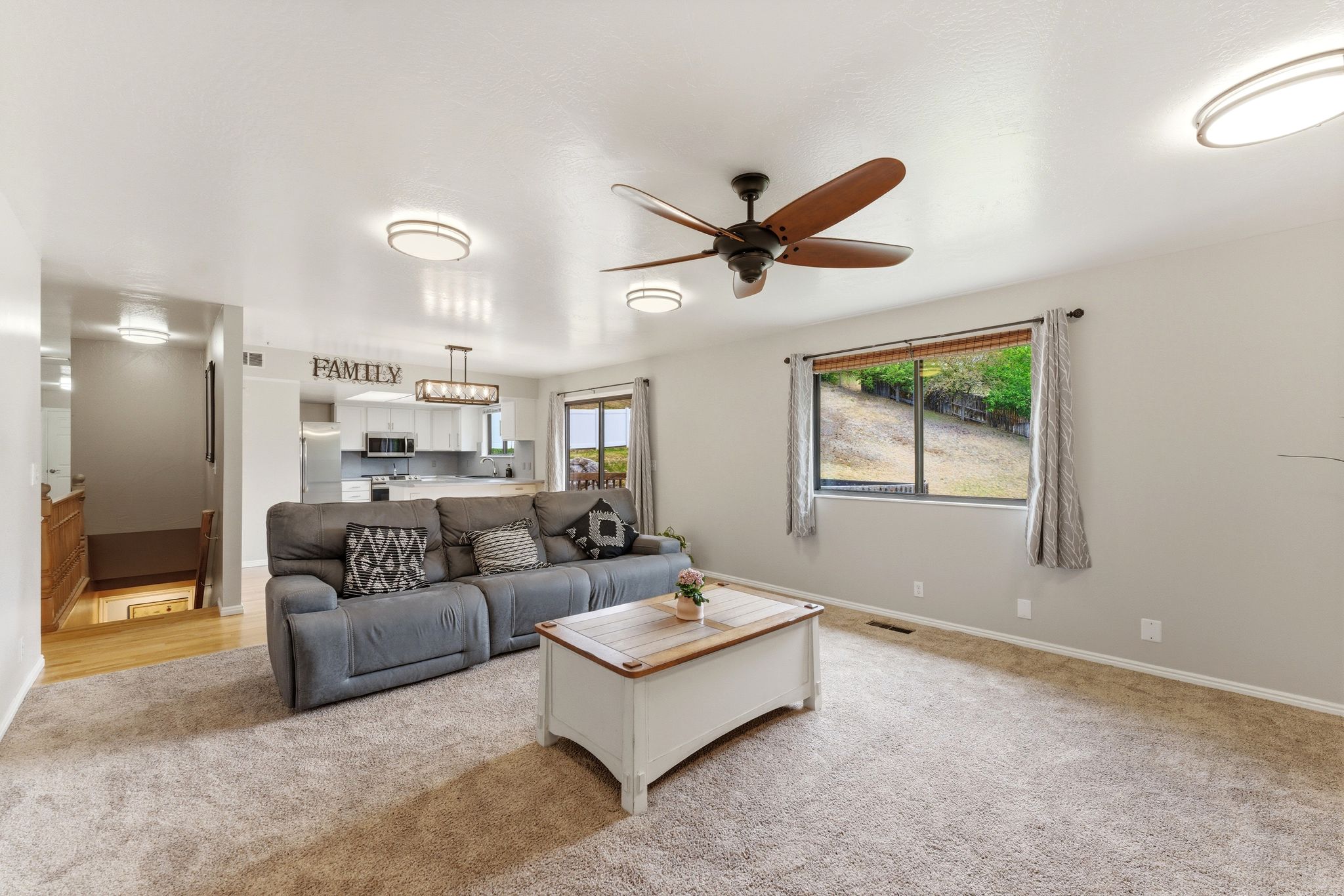 Spacious living area featuring neutral carpeting, a large window, and a ceiling fan