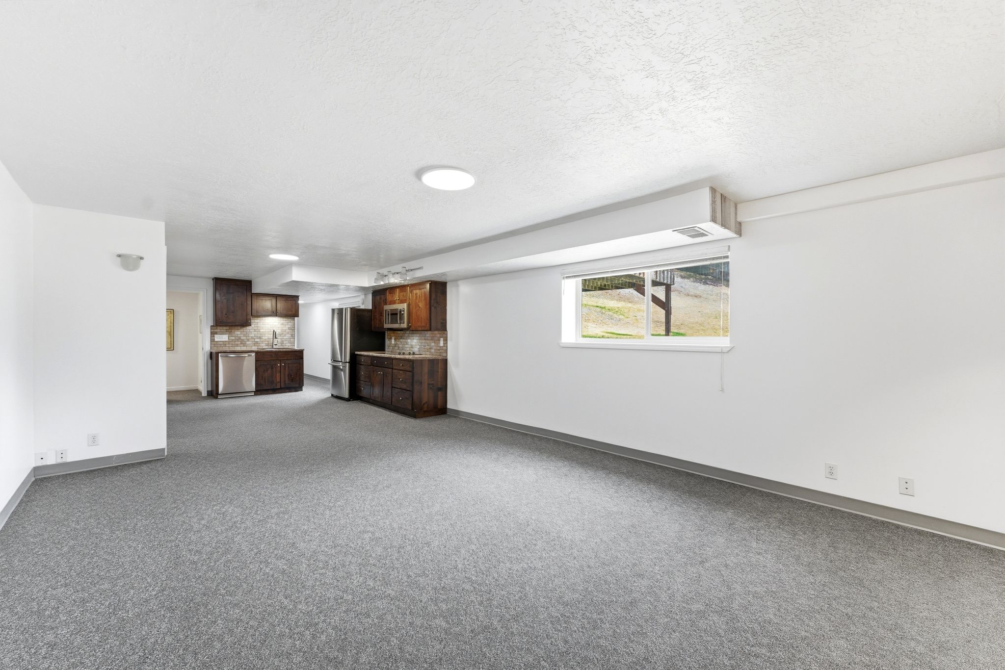 Open concept living area featuring gray carpeted flooring, white walls, and recessed lighting