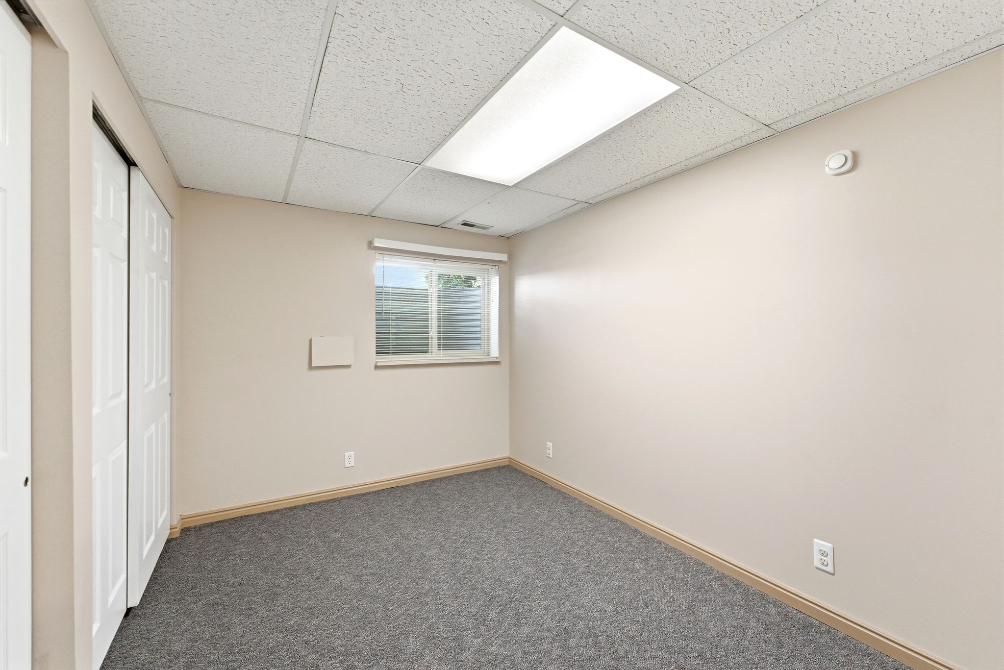 Room featuring neutral wall tones, gray carpeting, and white bi-fold closet doors