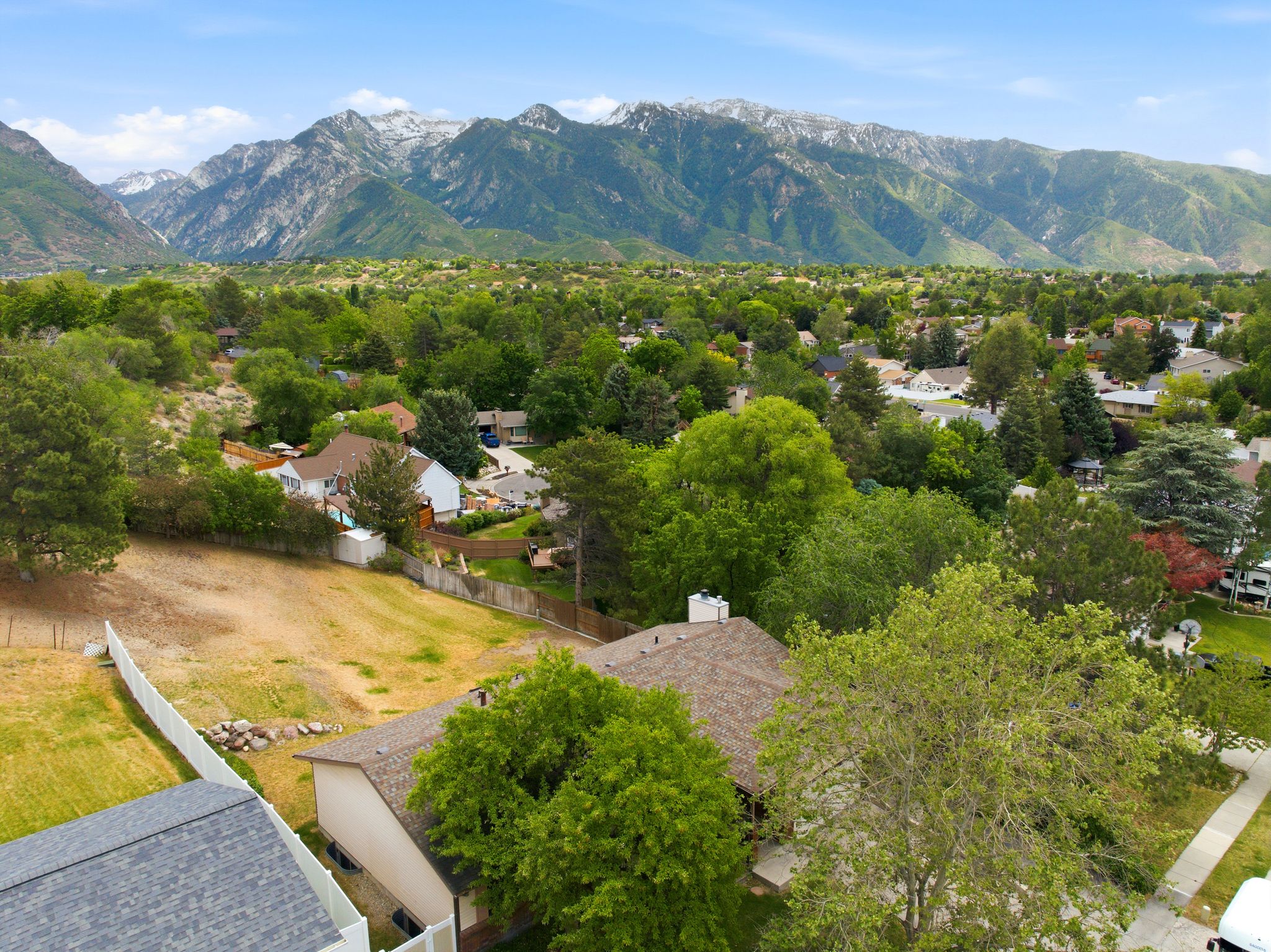 Expansive mountain range backdrop framing a residential area with mature trees and varied rooflines