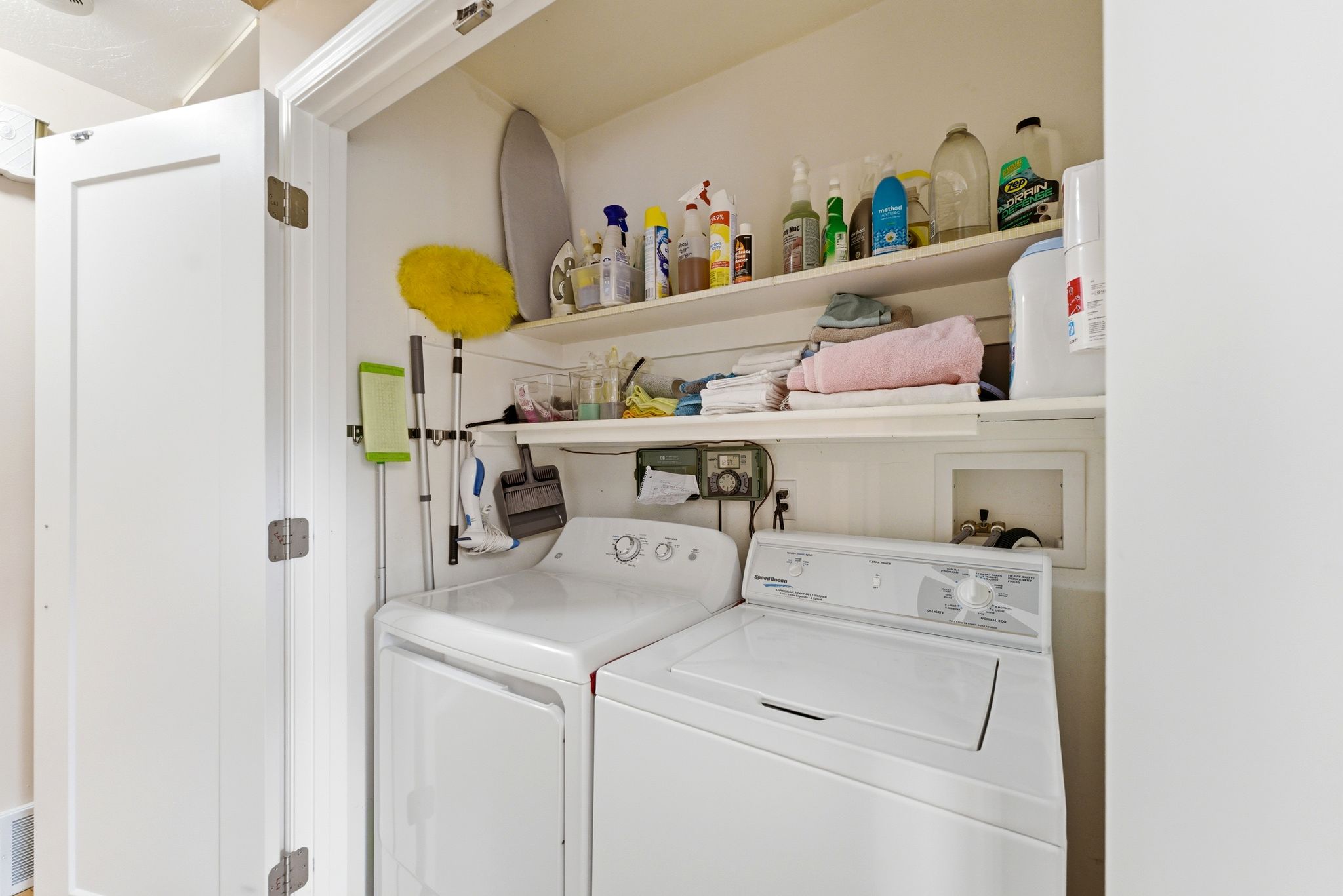Dedicated laundry closet featuring a top-loading washing machine, a front-loading dryer, and integrated shelving