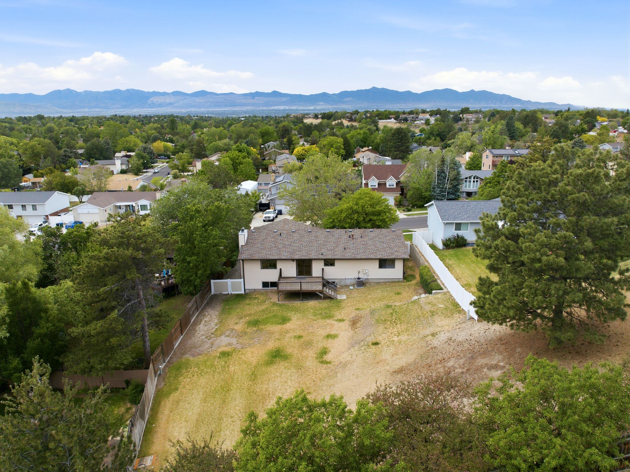 Expansive terraced lot featuring a wood deck, mature trees, and a mountain backdrop