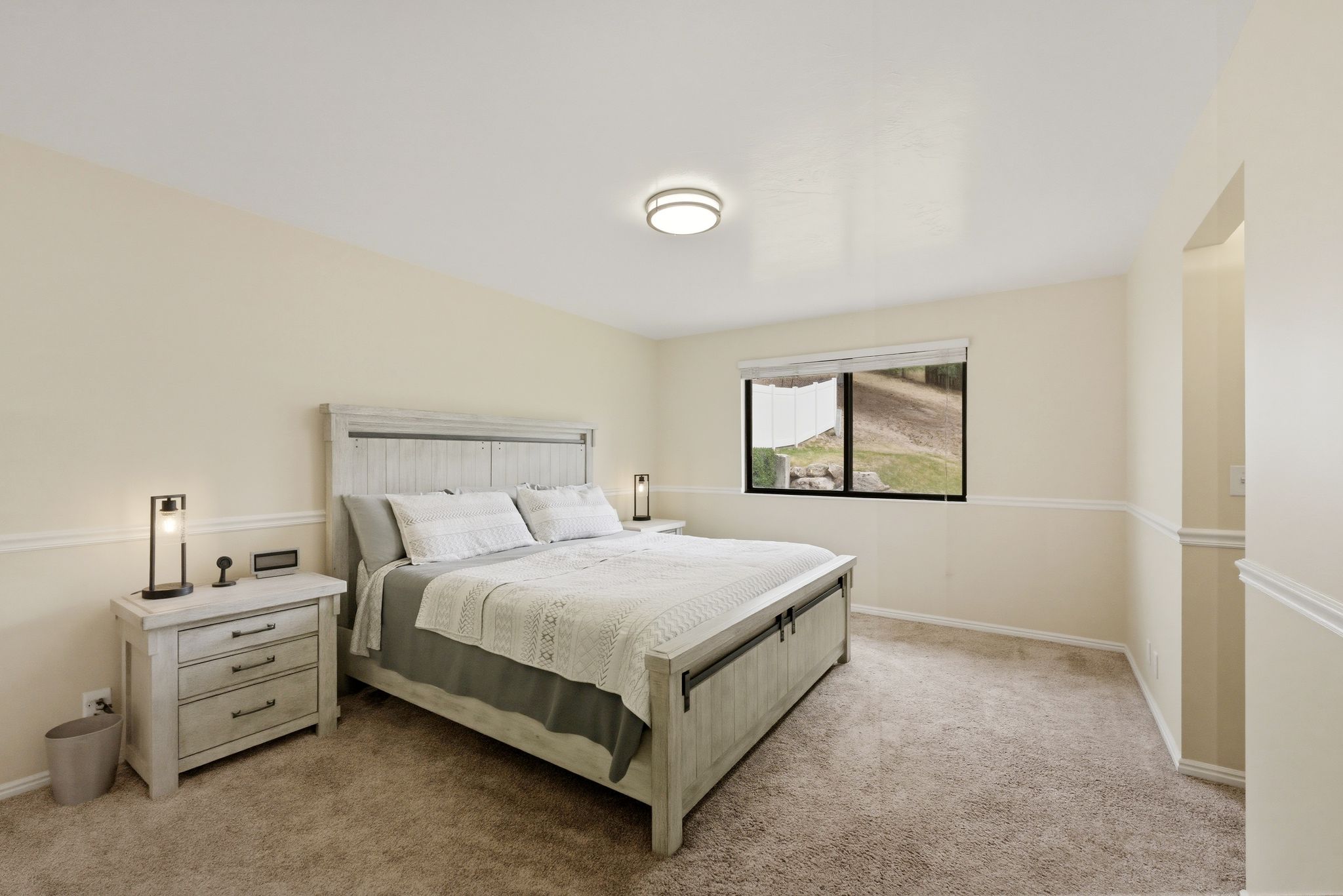 Spacious room featuring neutral wall tones, chair rail molding, and a built-in window with outdoor scenery