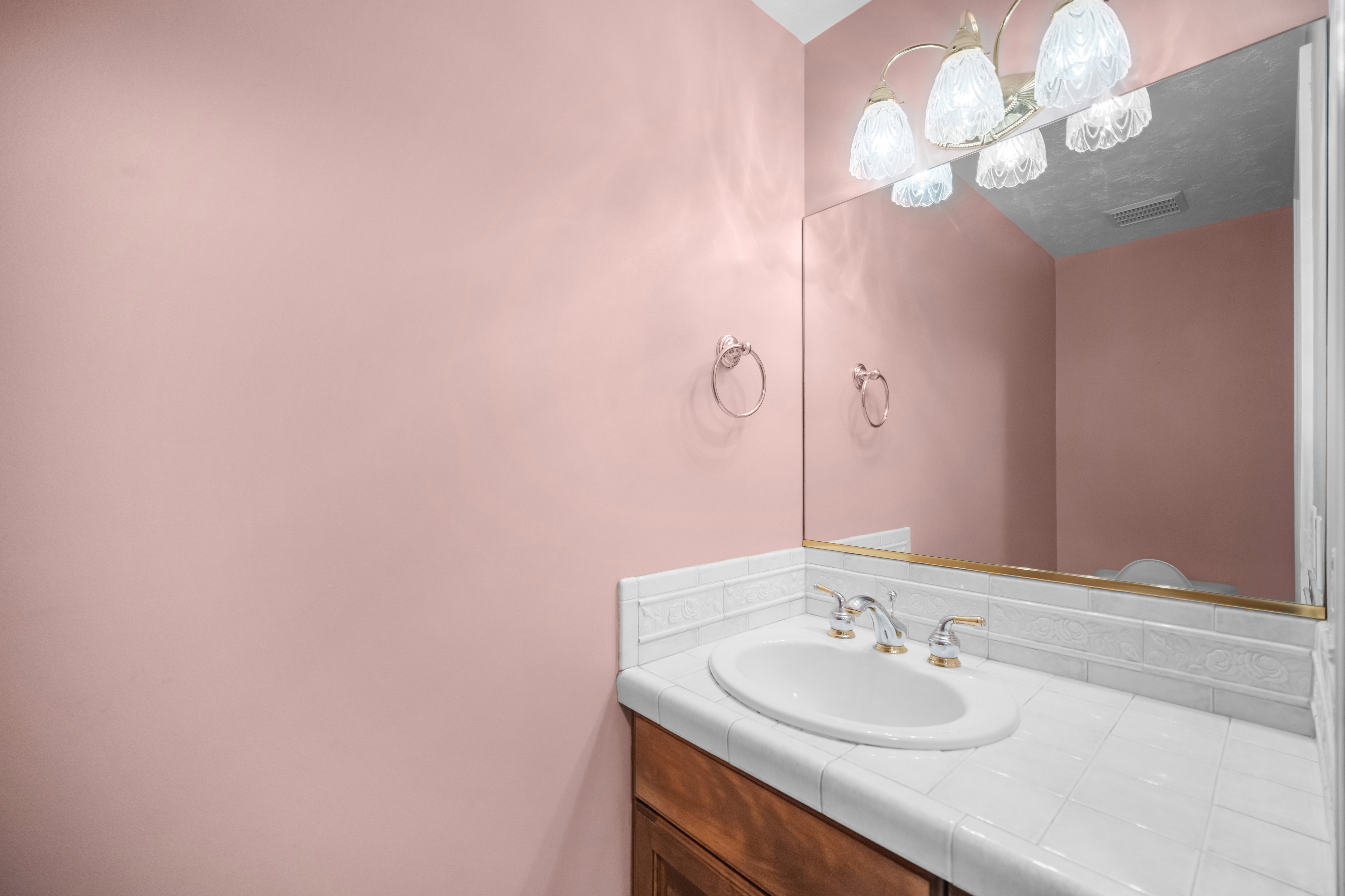Vanity featuring a white drop-in sink with a gold and chrome faucet, set into a tiled countertop with a matching tiled backsplash