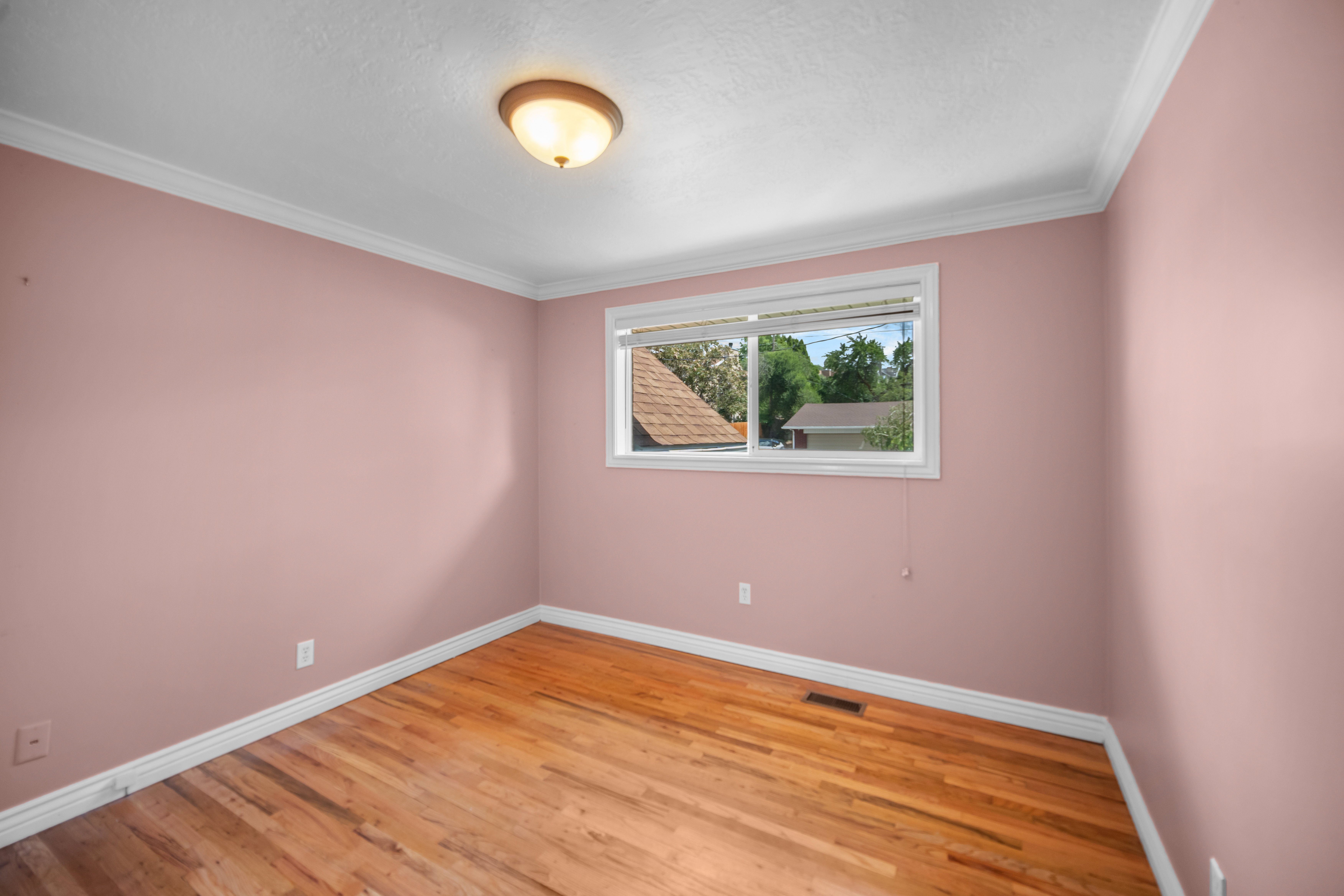 Hardwood flooring with white baseboards and crown molding