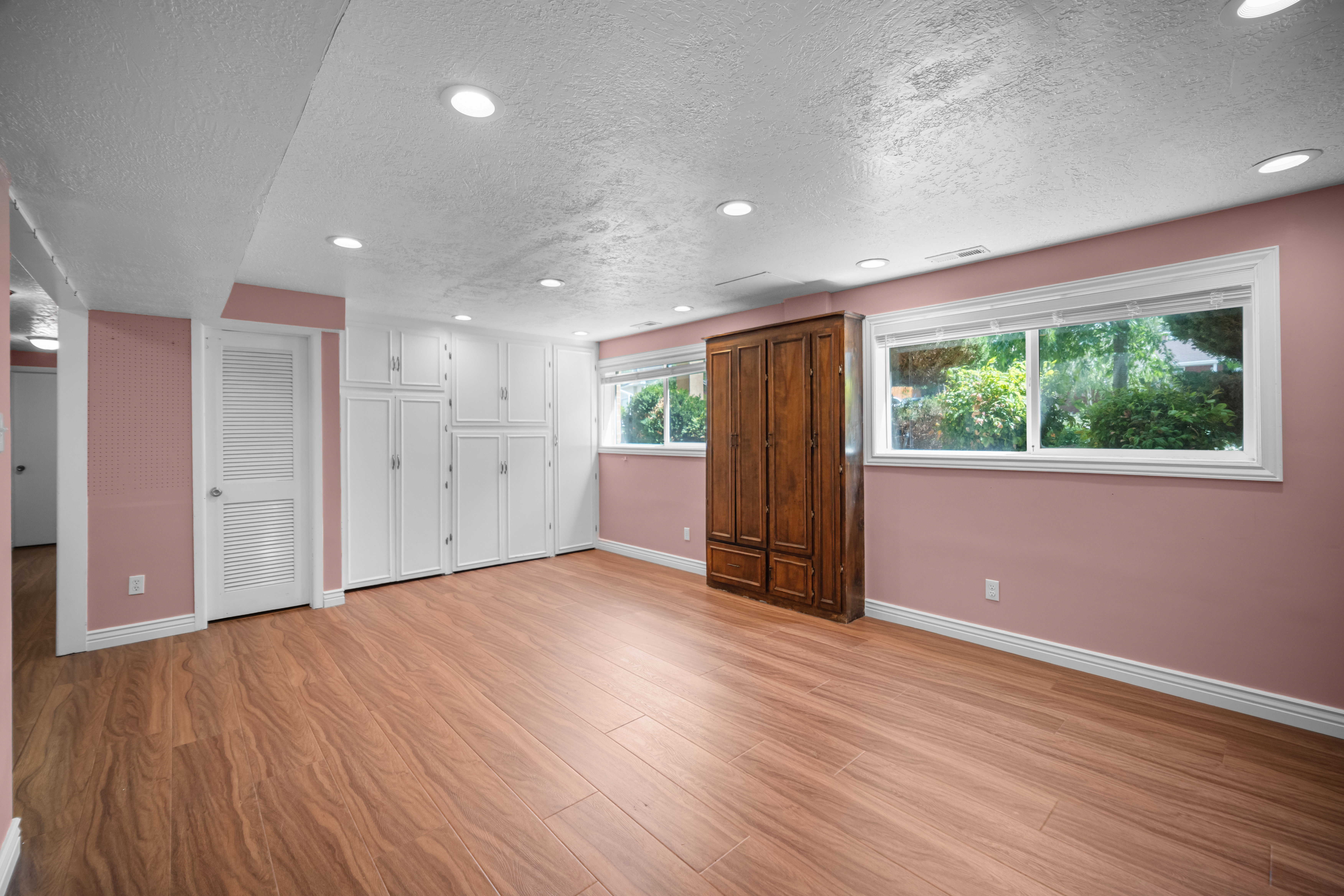 Spacious room featuring wood-finish flooring, recessed lighting, and two prominent windows