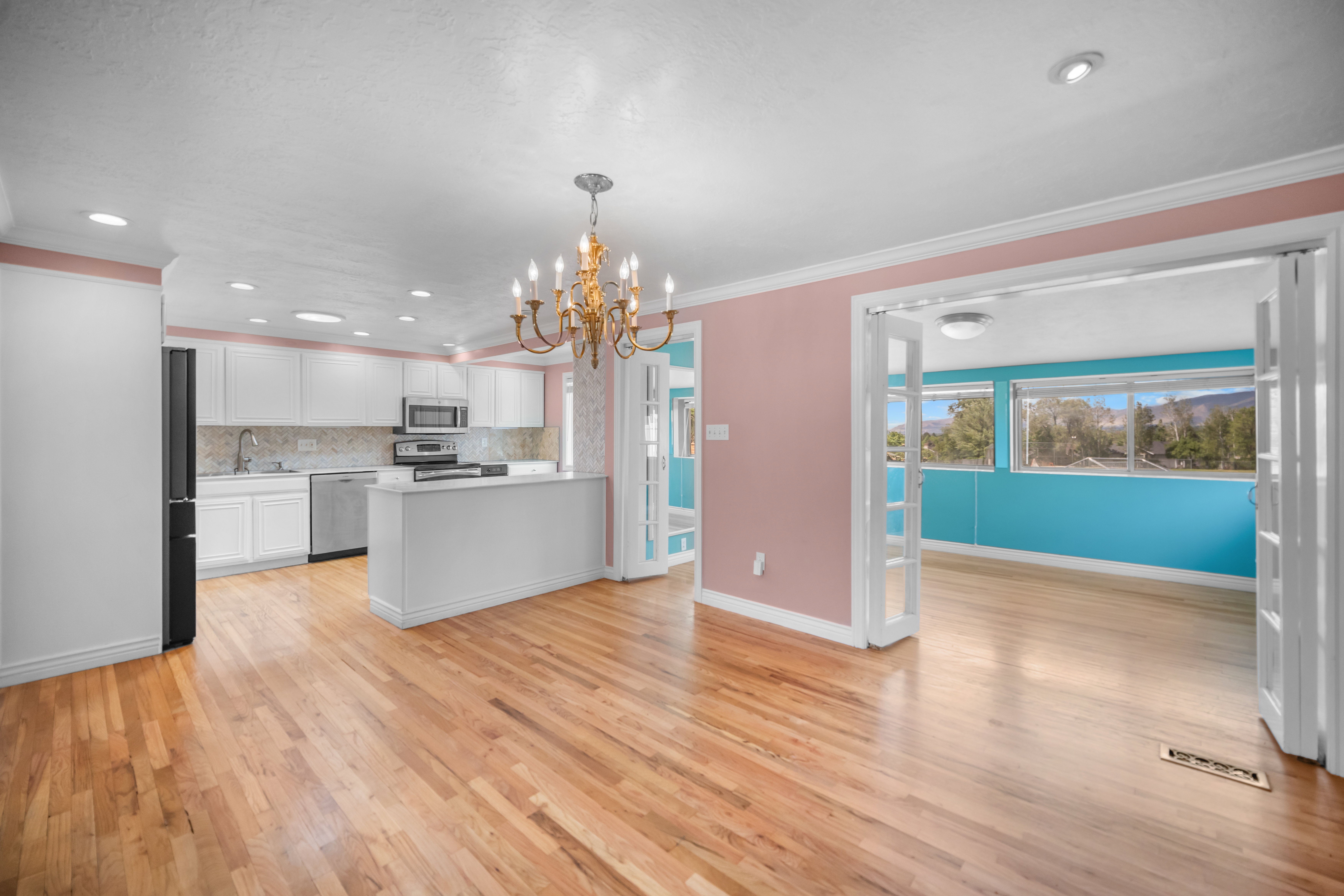 Open-concept kitchen and living area featuring wood-finish flooring, white cabinetry, and stainless steel appliances