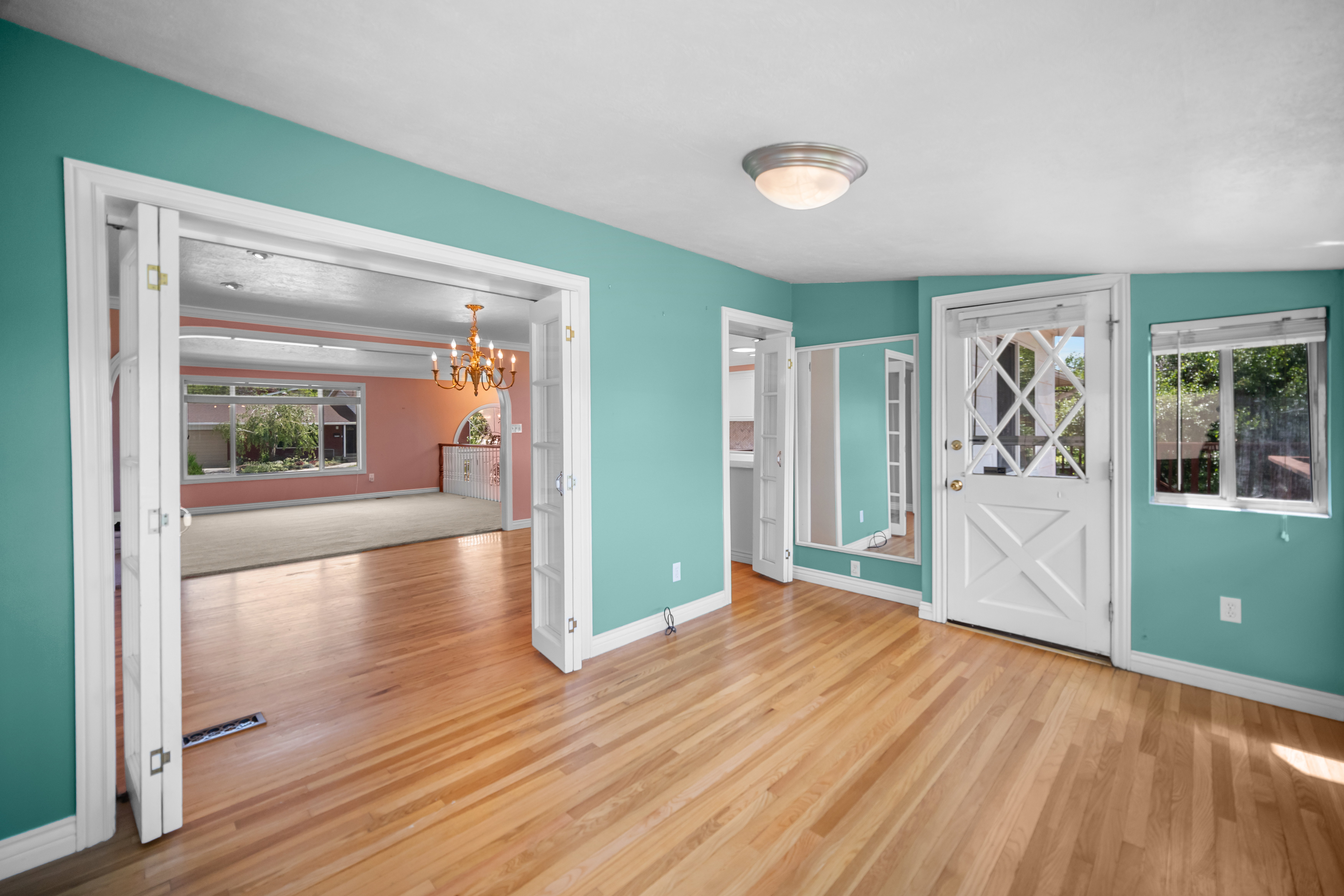 Hardwood flooring extending through a teal-painted room with white baseboards