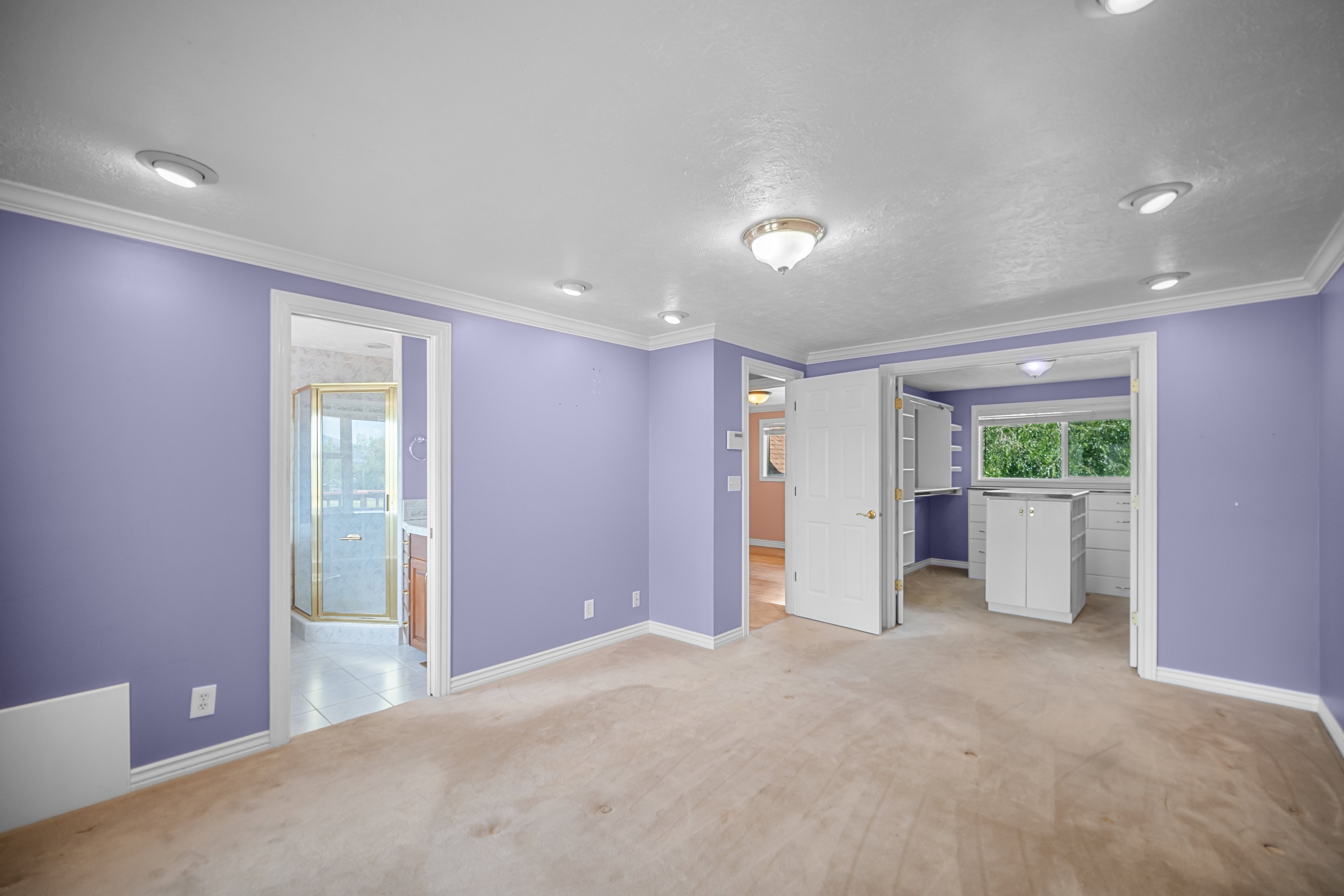 Carpeted room featuring recessed lighting, a ceiling-mounted light fixture, white trim, and a doorway leading to a bathroom with a glass-enclosed shower