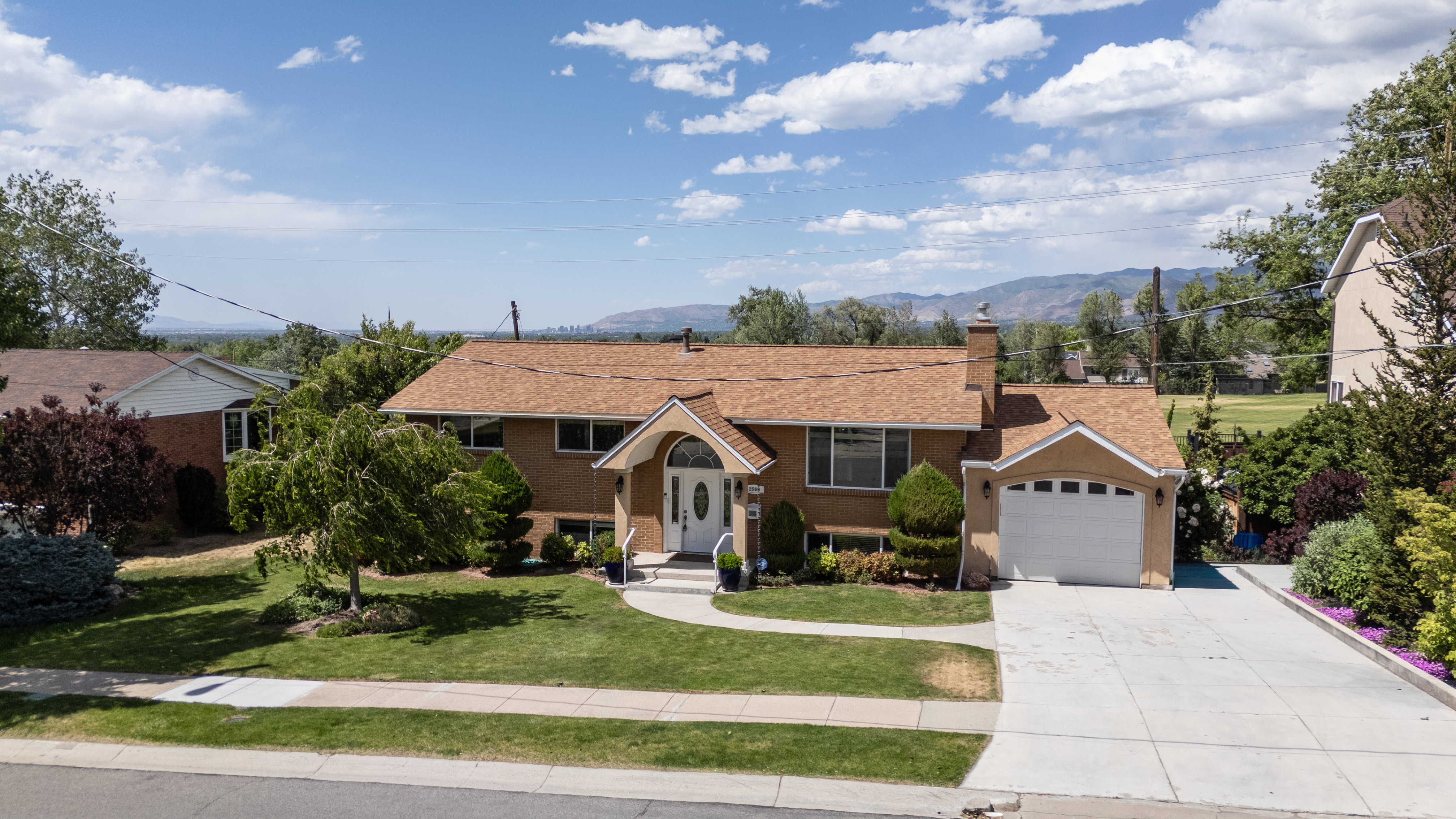Traditional-style residence featuring a prominent arched entry, attached two-car garage, and a concrete driveway