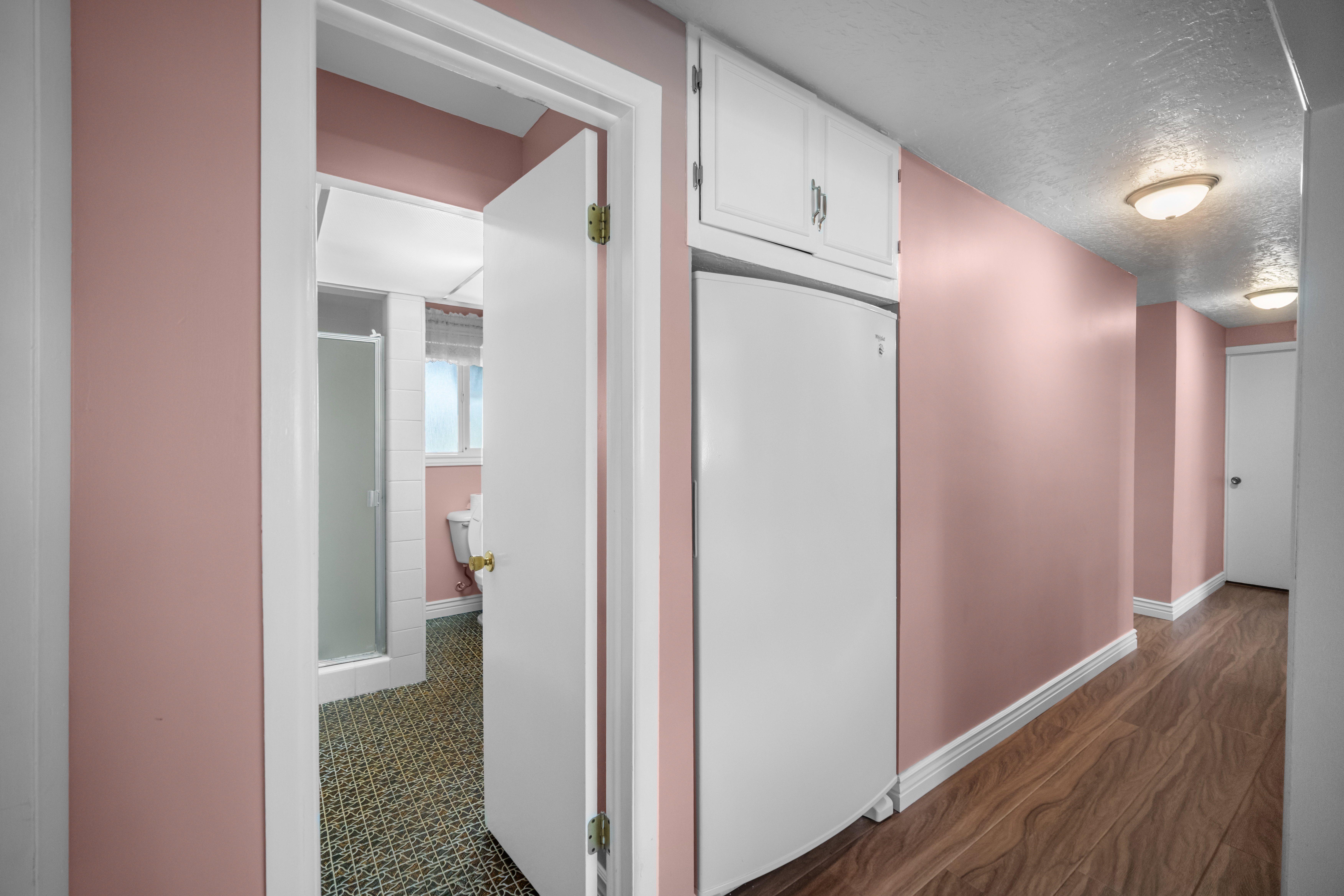 Hallway with wood-finish flooring, white baseboards, and built-in white cabinets