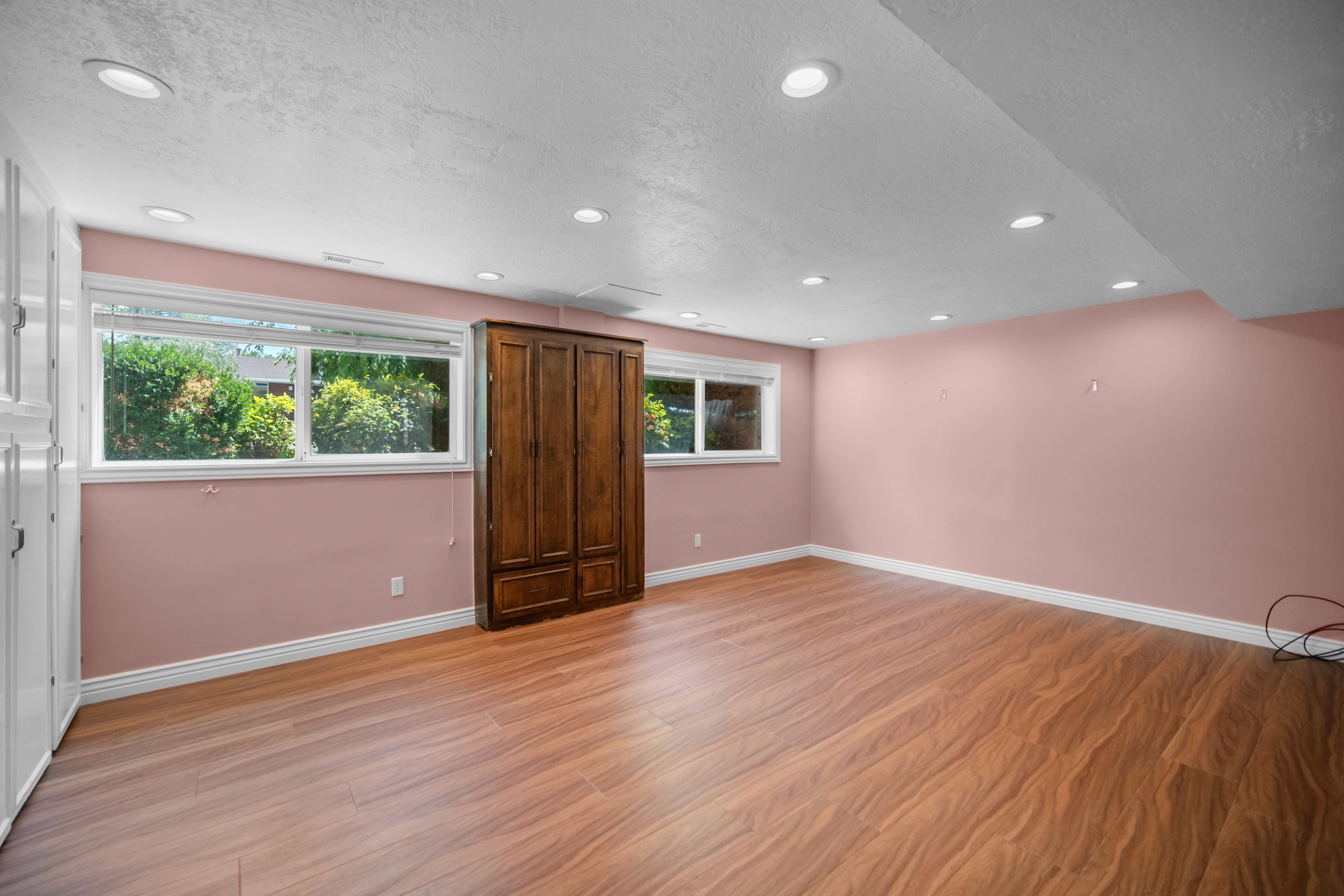 Spacious room featuring wood-finish flooring, recessed lighting, and multiple windows