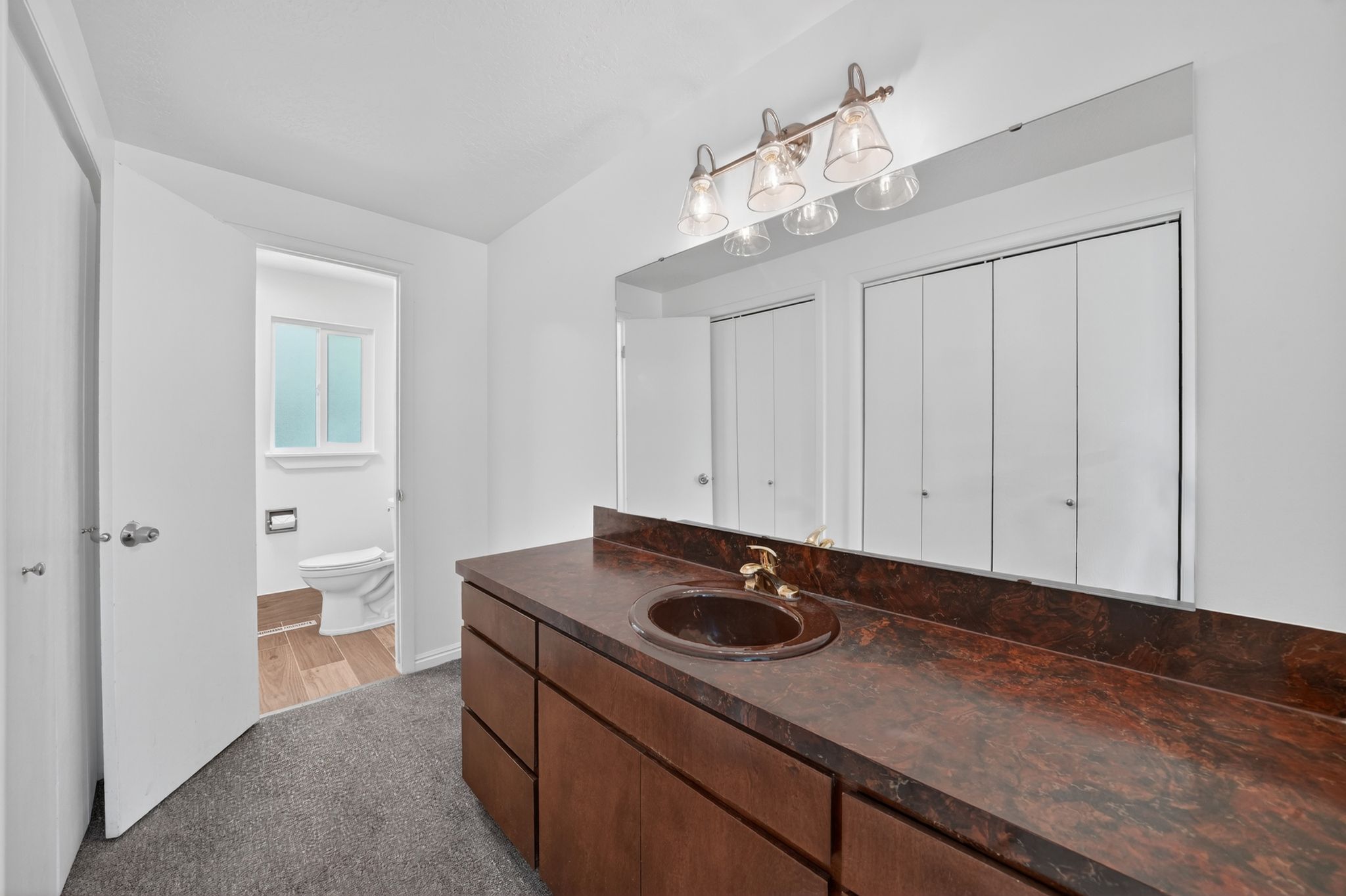Priamary Bathroom vanity featuring an integrated sink, broad mirror, and warm wood-finish cabinetry