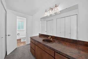 Priamary Bathroom vanity featuring an integrated sink, broad mirror, and warm wood-finish cabinetry