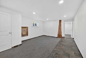 Spacious room featuring recessed lighting, a window with louvered shutters, and a unique wood architectural element