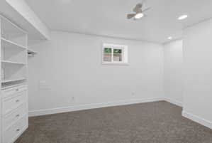 Bedroom featuring built-in white cabinetry with drawers and shelving, gray carpeting, a window with exterior visibility, recessed lighting, and a ceiling fan