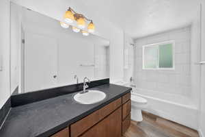 Main Level Bathroom featuring a wide vanity mirror, a dark countertop, an undermount sink, and a wood-finish vanity with drawers