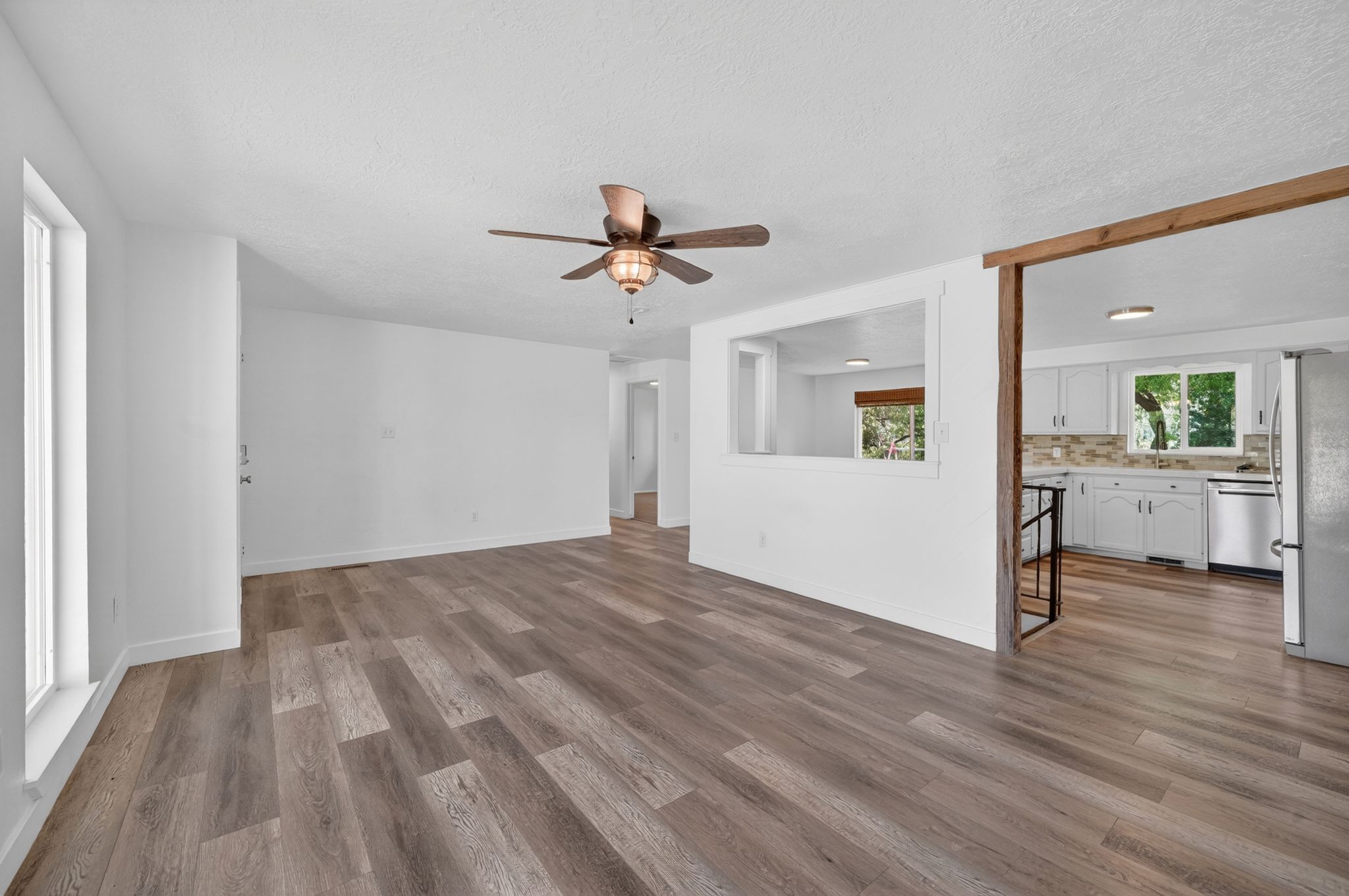 Open-concept living space featuring wood-finish flooring, white walls, and a ceiling fan