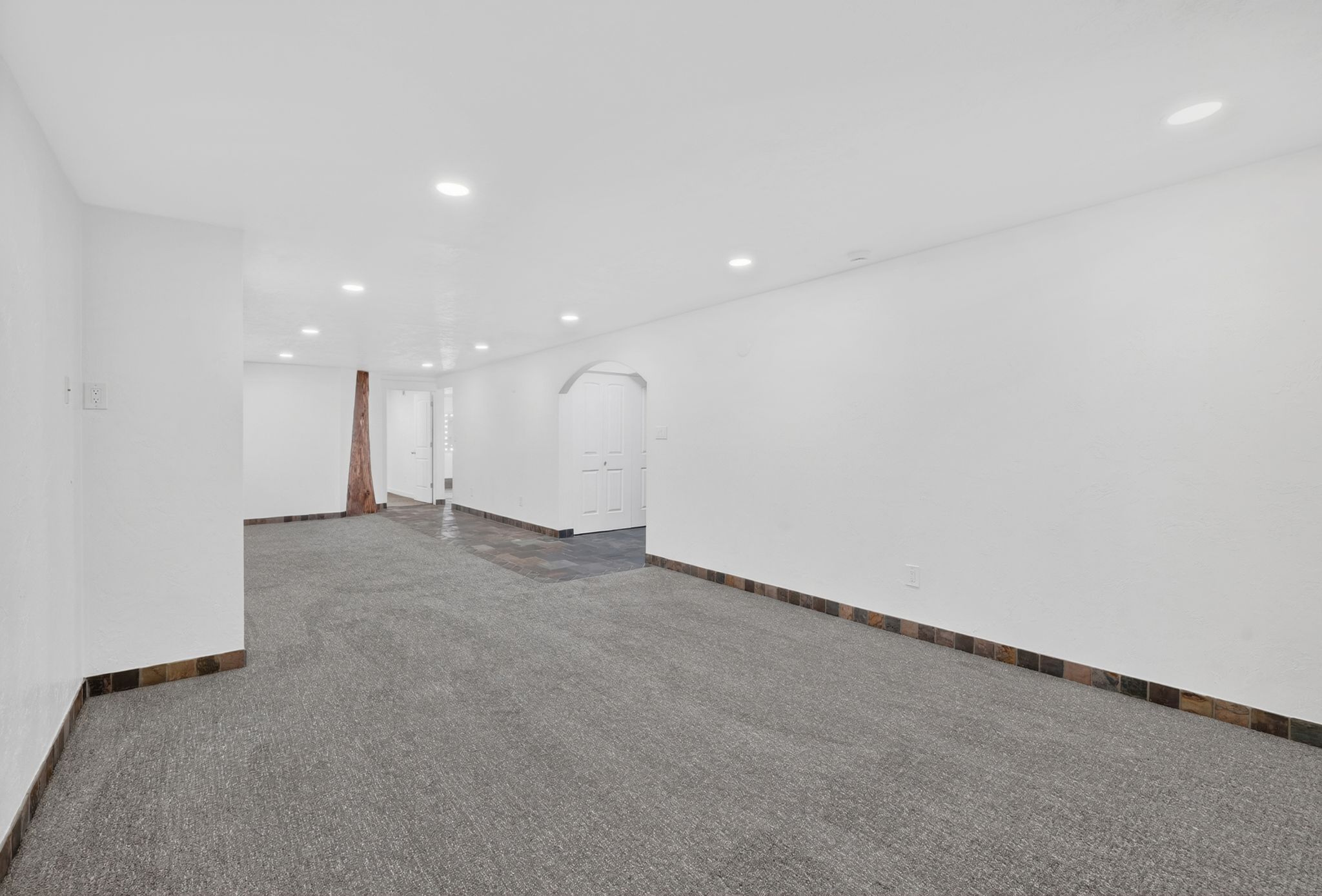Spacious interior featuring recessed lighting, white walls, and a combination of gray carpeting and dark tile flooring
