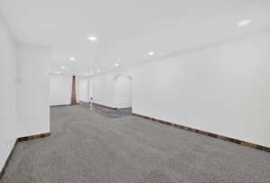 Spacious interior featuring recessed lighting, white walls, and a combination of gray carpeting and dark tile flooring