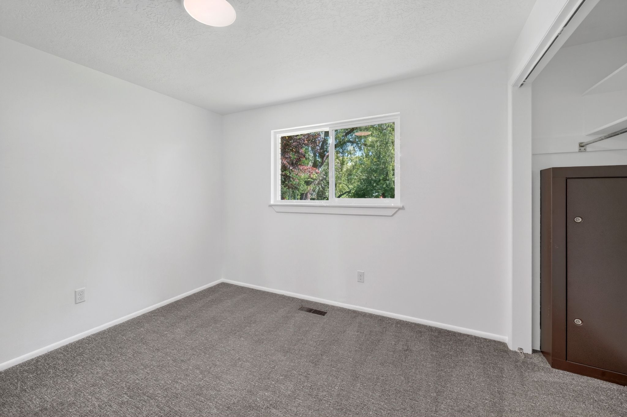 Bedroom featuring neutral-toned walls, gray carpeting, and a window with exterior views