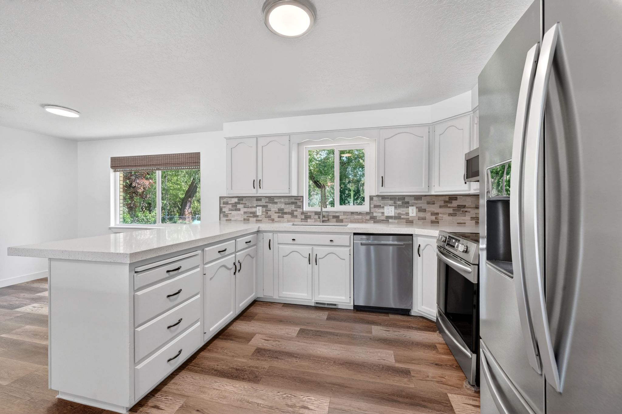 Modern kitchen featuring white cabinetry, a large center island with a light-toned countertop, and stainless steel appliances
