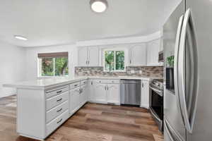 Modern kitchen featuring white cabinetry, a large center island with a light-toned countertop, and stainless steel appliances