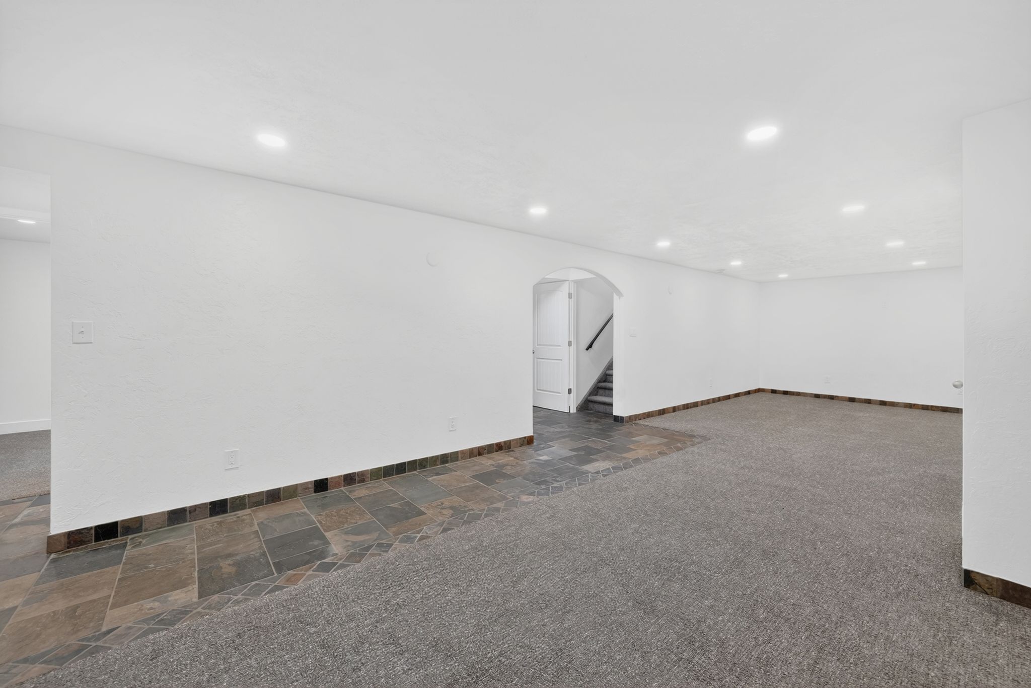 Spacious room featuring recessed lighting, a combination of carpet and slate tile flooring, and white walls