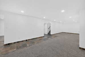 Spacious room featuring recessed lighting, a combination of carpet and slate tile flooring, and white walls