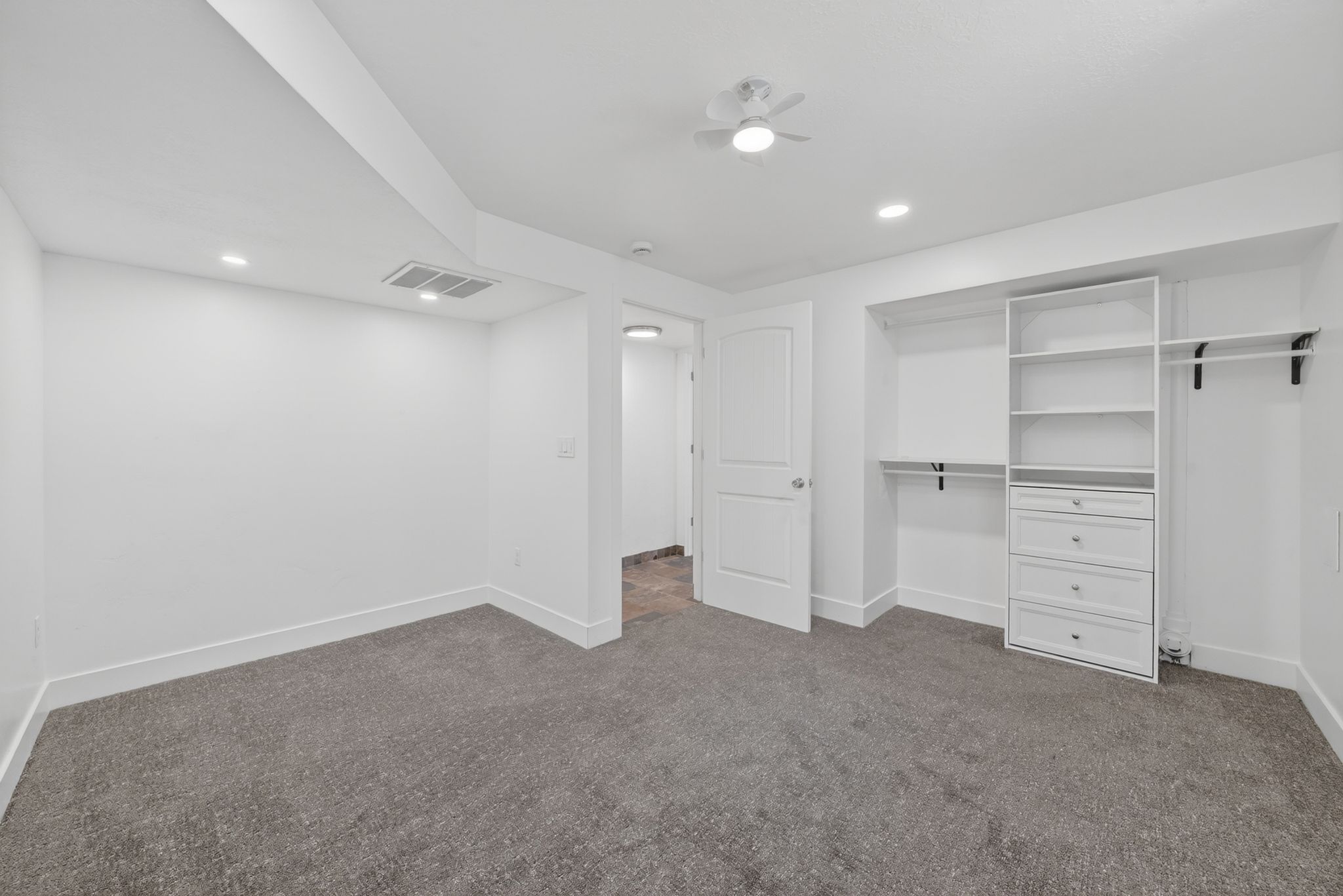 Carpeted room featuring recessed lighting, a ceiling fan, white baseboards, and a custom built-in closet system with shelving and drawers