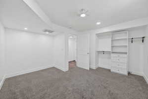Carpeted room featuring recessed lighting, a ceiling fan, white baseboards, and a custom built-in closet system with shelving and drawers