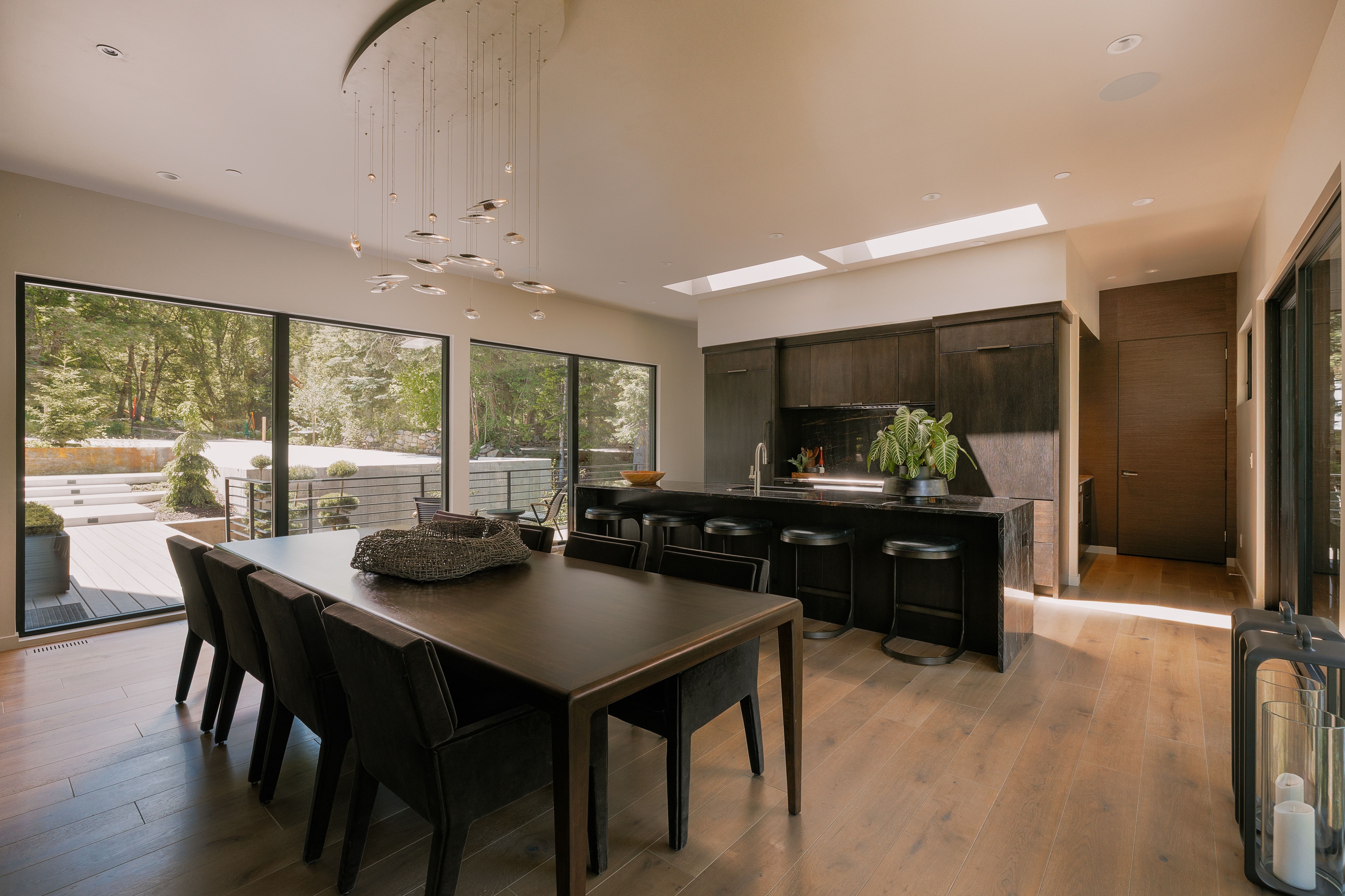 Open-concept living area featuring wood-finish flooring, a contemporary chandelier, and a kitchen island with seating