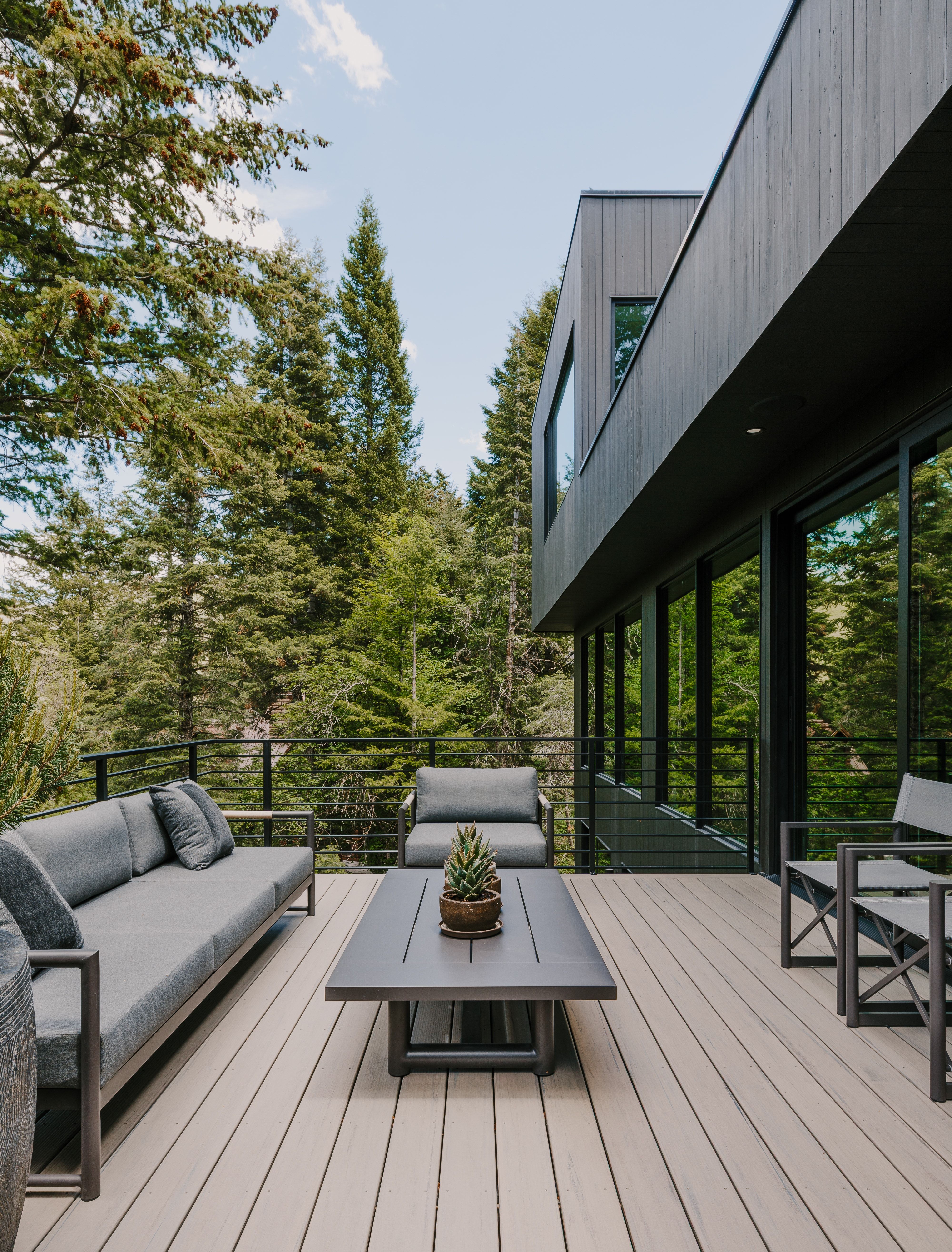 Expansive outdoor deck featuring wood-finish decking, a black metal railing, and extensive surrounding mature trees