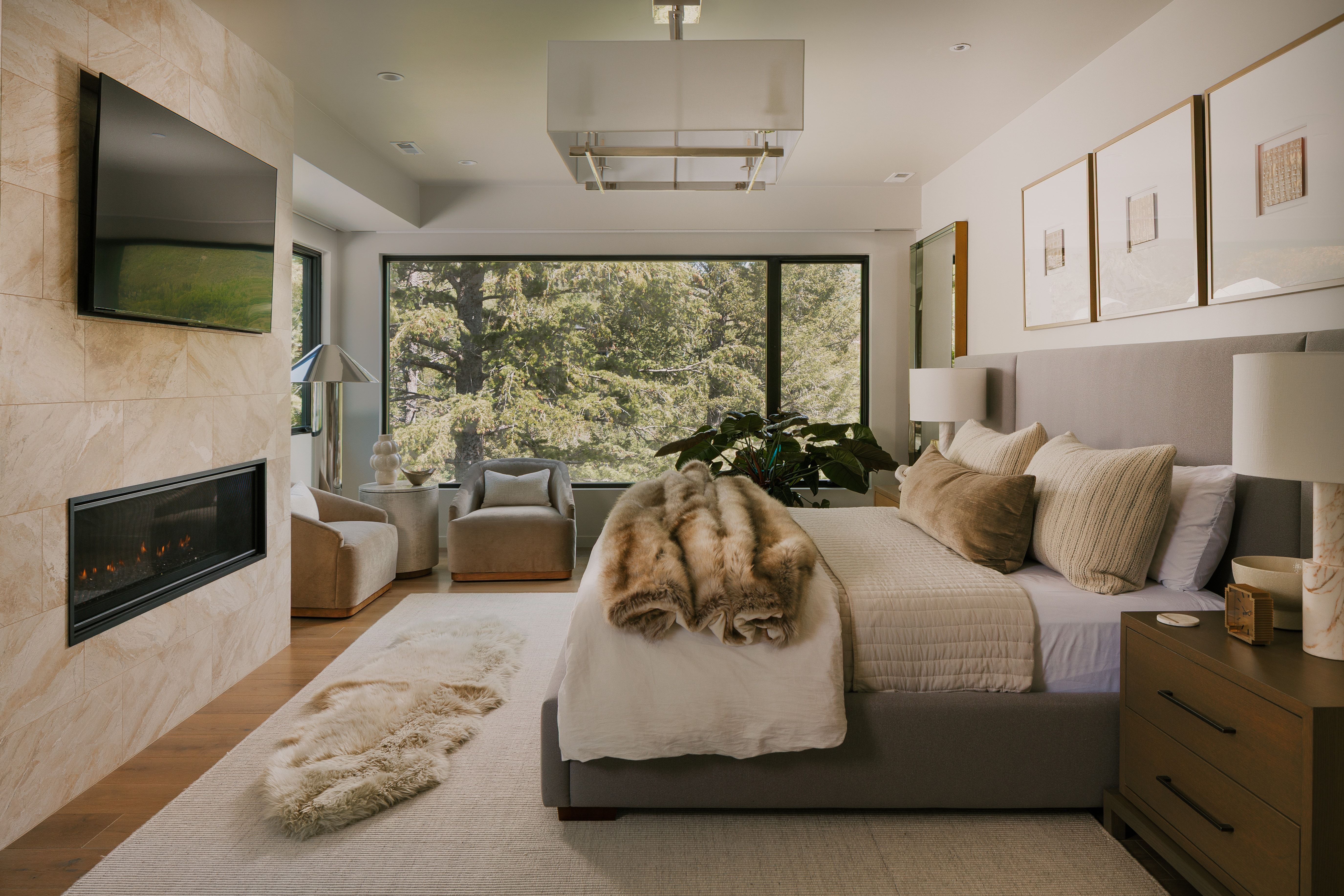 Expansive window framing a wooded landscape, complemented by a tiled accent wall with an inset fireplace