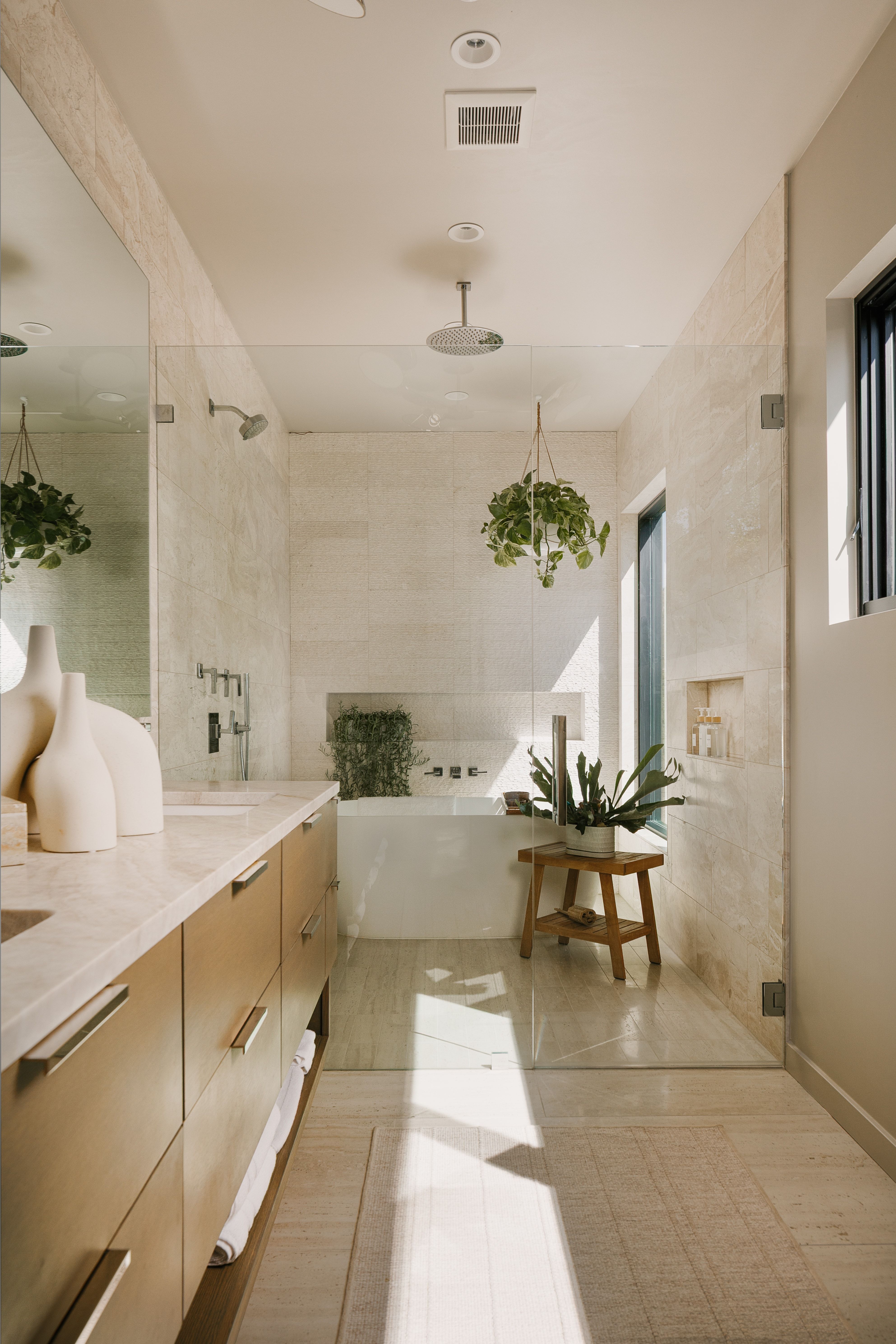 Contemporary bathroom featuring a freestanding tub, glass-enclosed shower with dual showerheads, wood-finish vanity with stone countertop, and recessed lighting