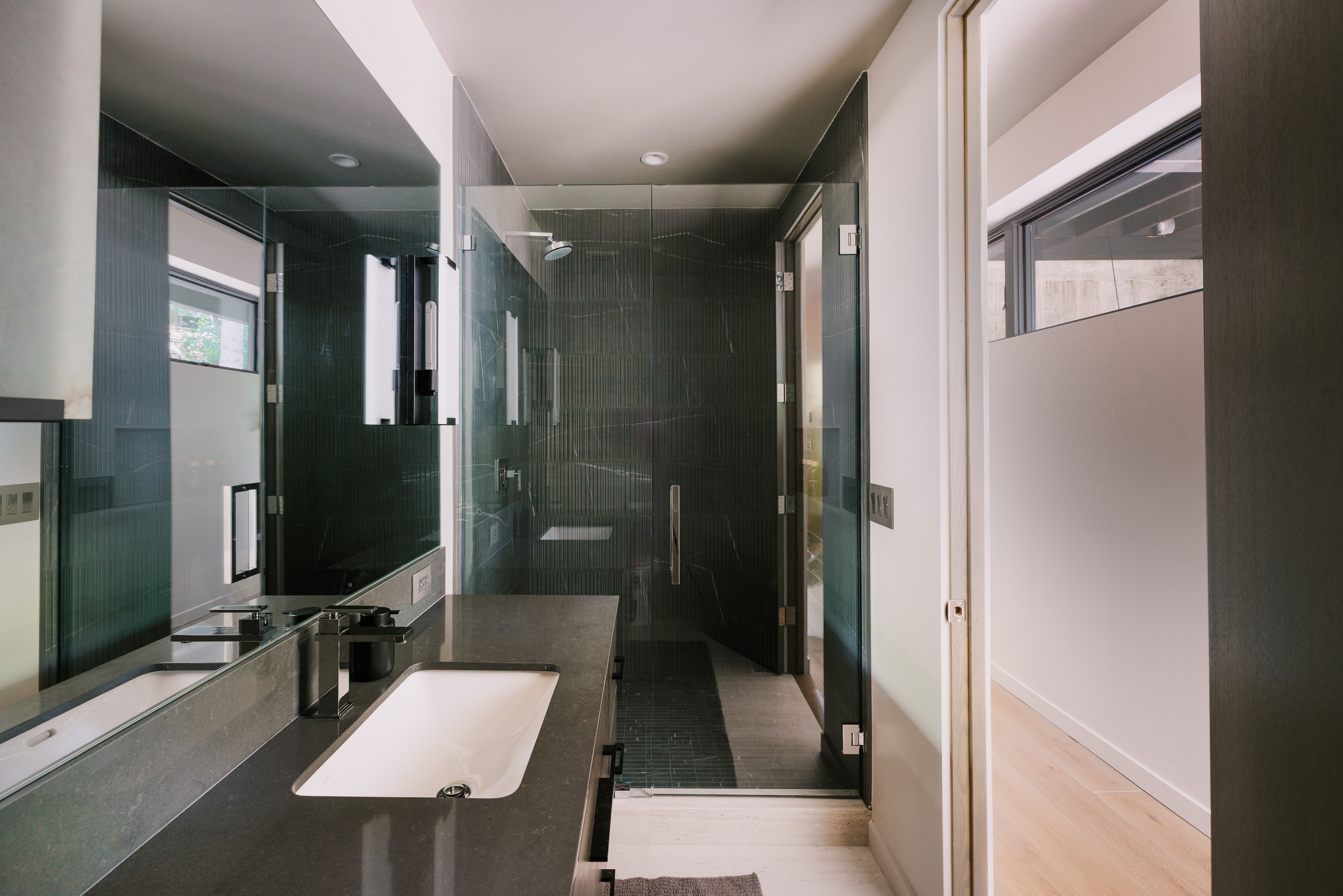Modern bathroom featuring a dark stone-finish vanity with an integrated rectangular sink and a wall-mounted faucet