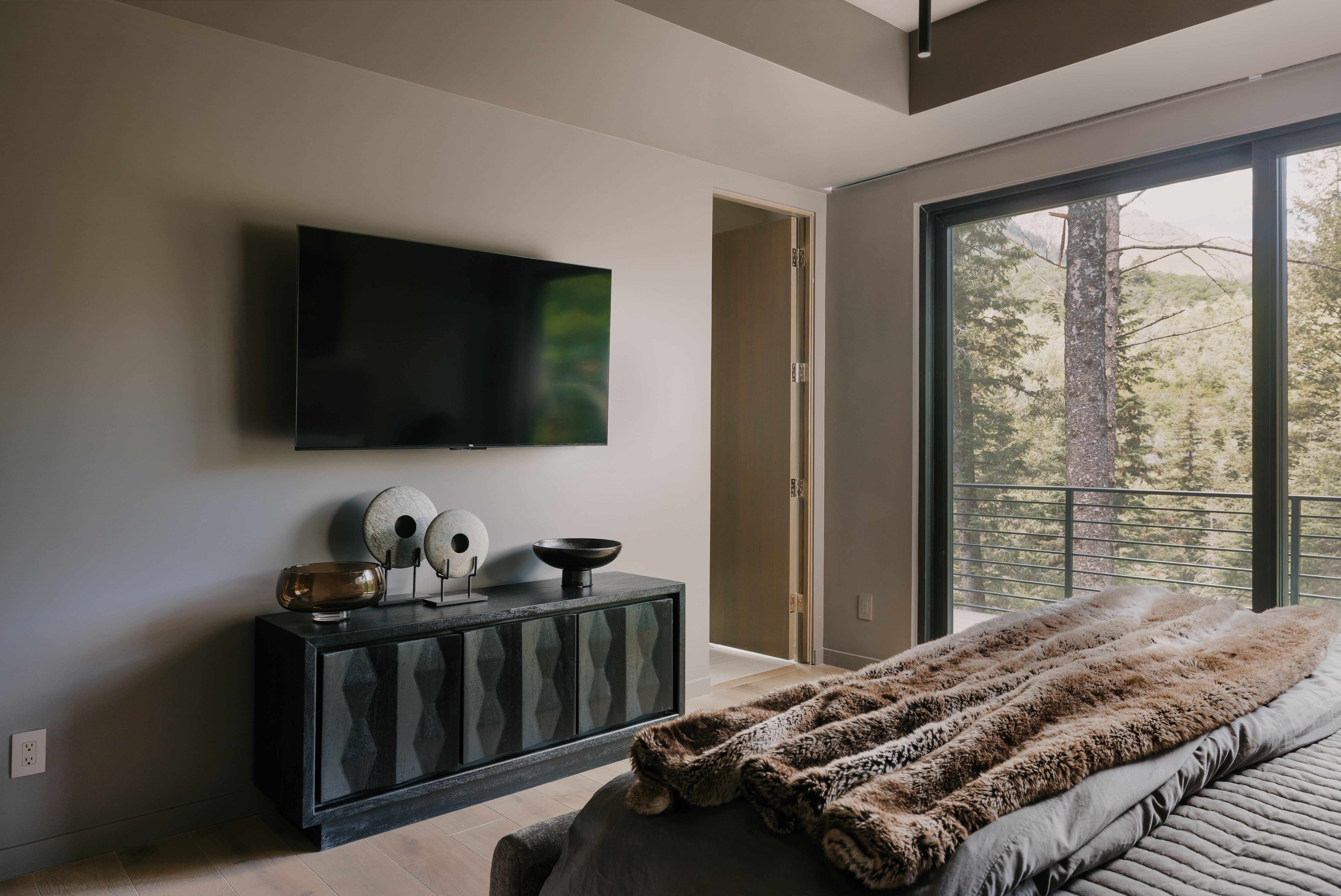 Floor-to-ceiling sliding glass doors with dark frames, wood-finish flooring, recessed lighting, and a neutral wall color