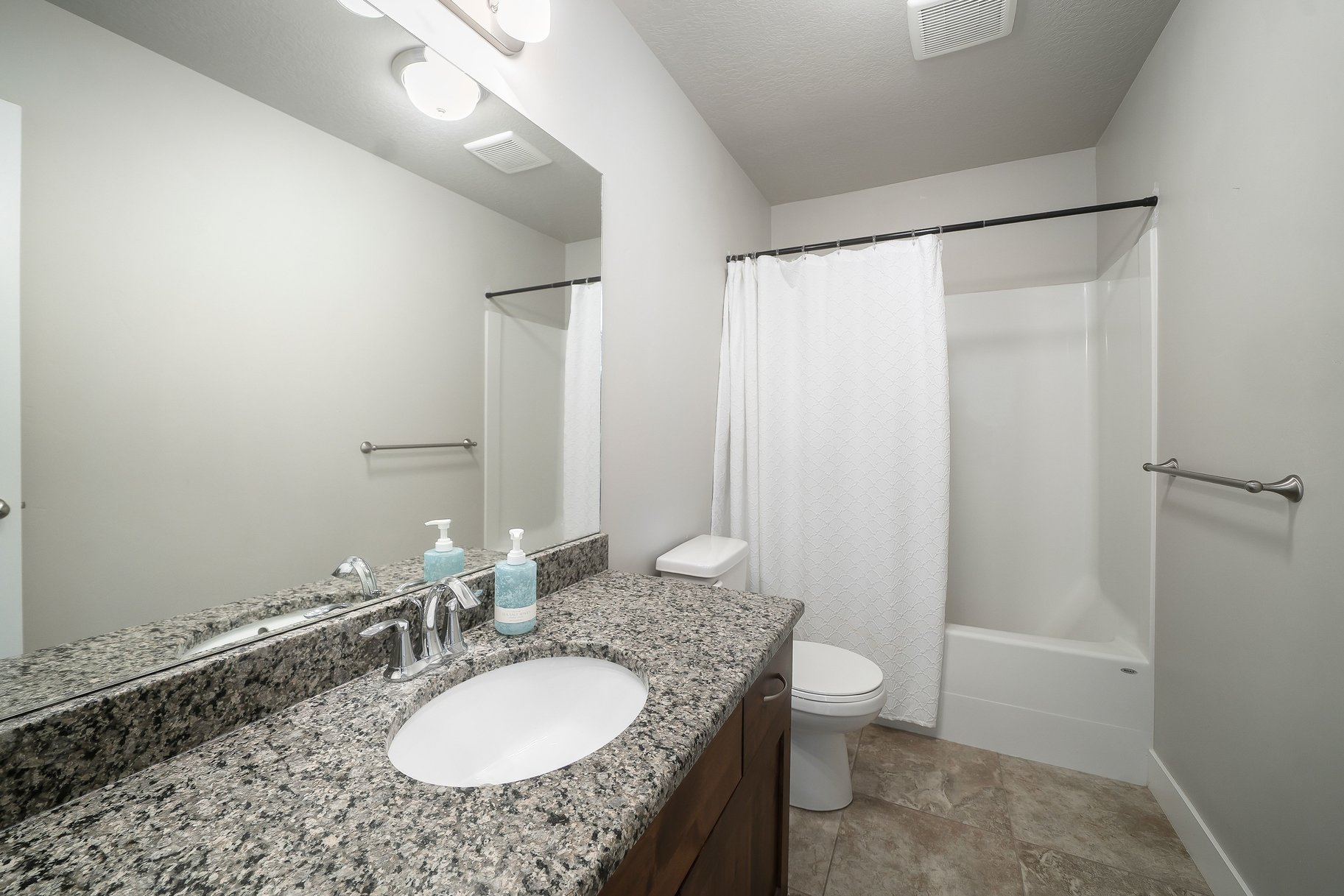 Bathroom featuring a dark wood vanity with a granite countertop, undermount sink, and polished chrome faucet