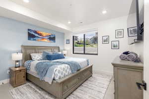 Spacious bedroom featuring light-colored carpeting, recessed lighting, and a large window with black framing