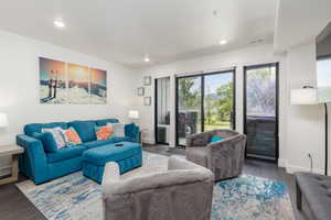 Living area featuring dark wood-finish flooring, recessed lighting, and white baseboards