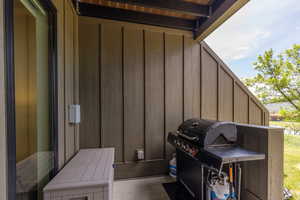 Private patio featuring vertical wood panel siding and an overhead deck with slatted wood details